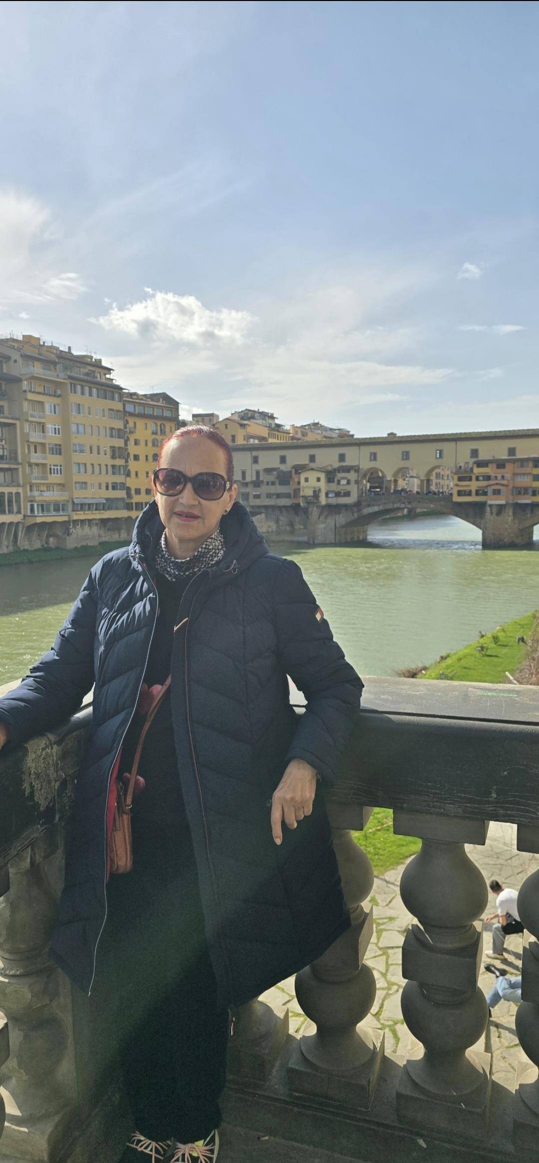 Tourist enjoys the sunny weather while exploring Florence near the iconic Arno River.
