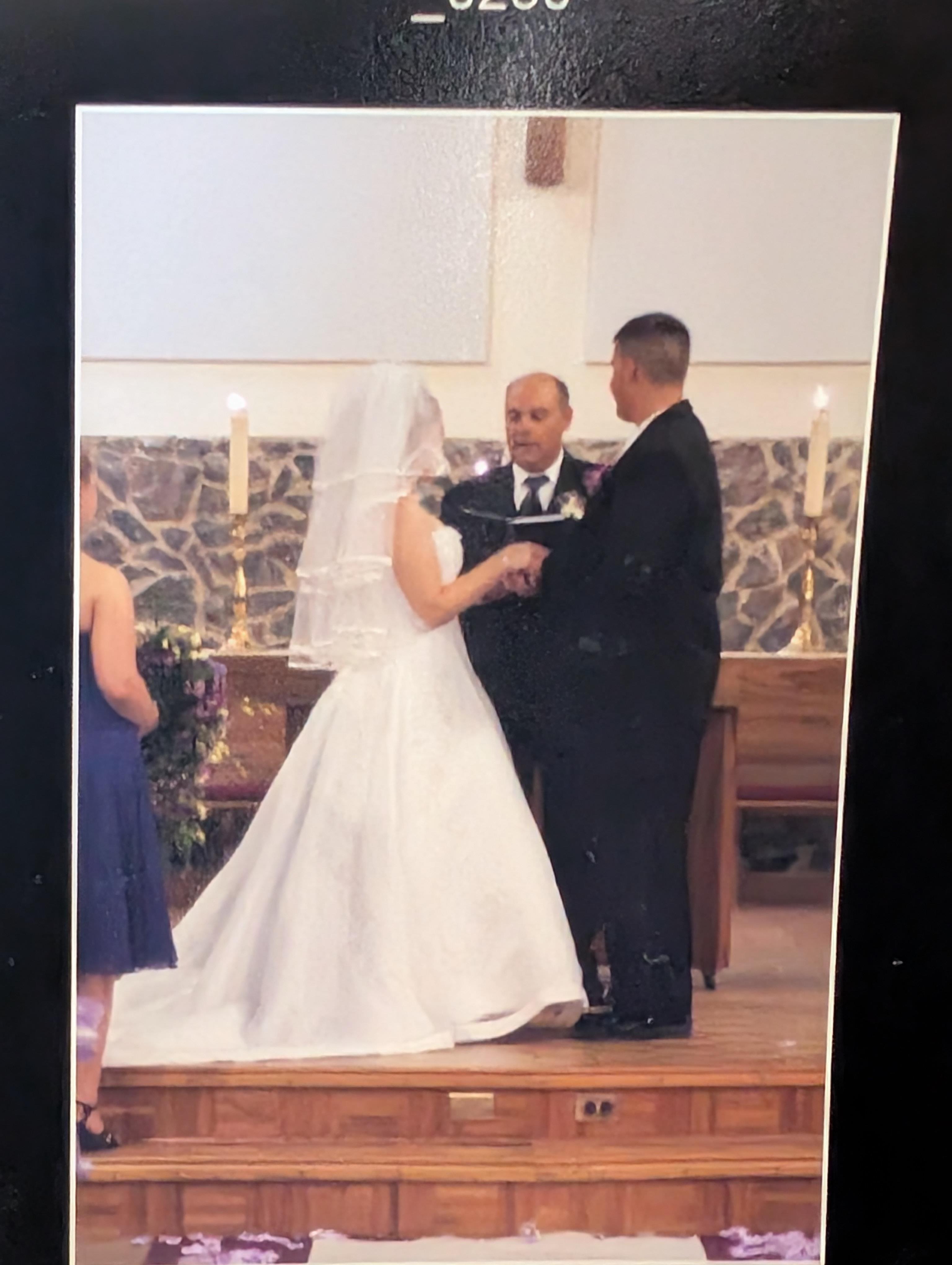 A couple stands at the altar with a officiant as they exchange vows surrounded by candles.