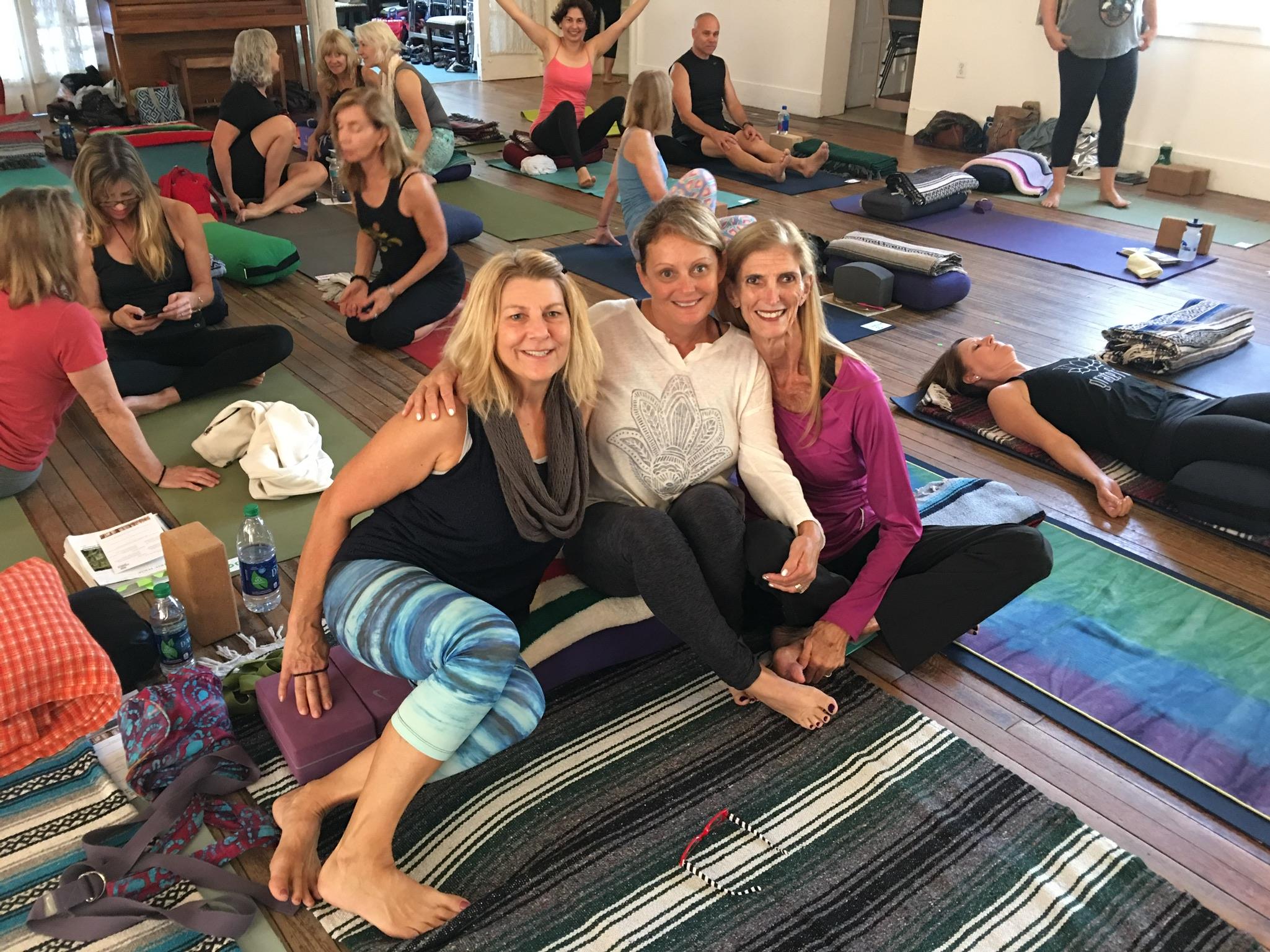 Women participate in a yoga session in a bright, airy studio focusing on wellness and relaxation.