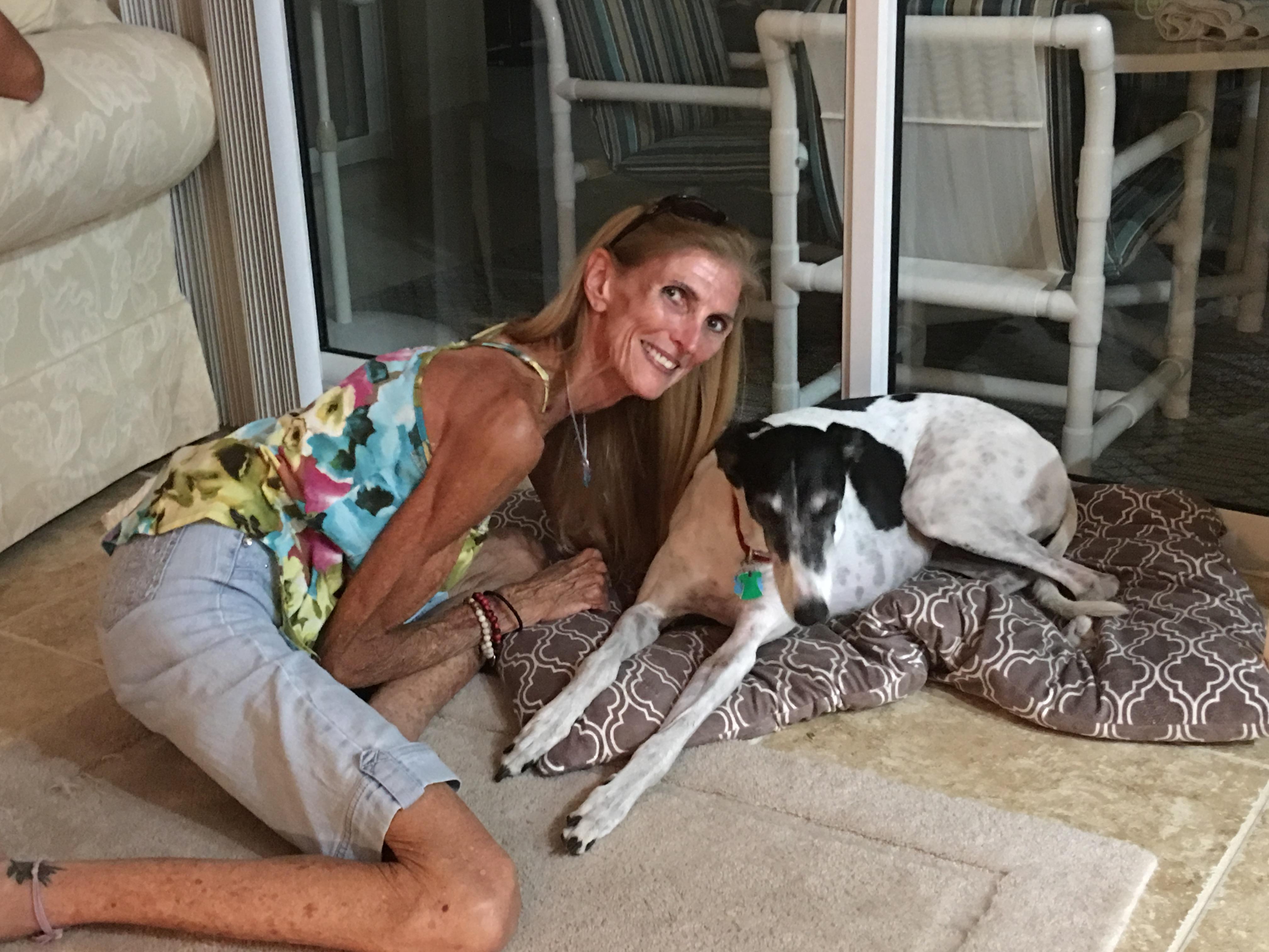 Woman kneels next to her dog in a warm, inviting living room, highlighting their bond and comfort.