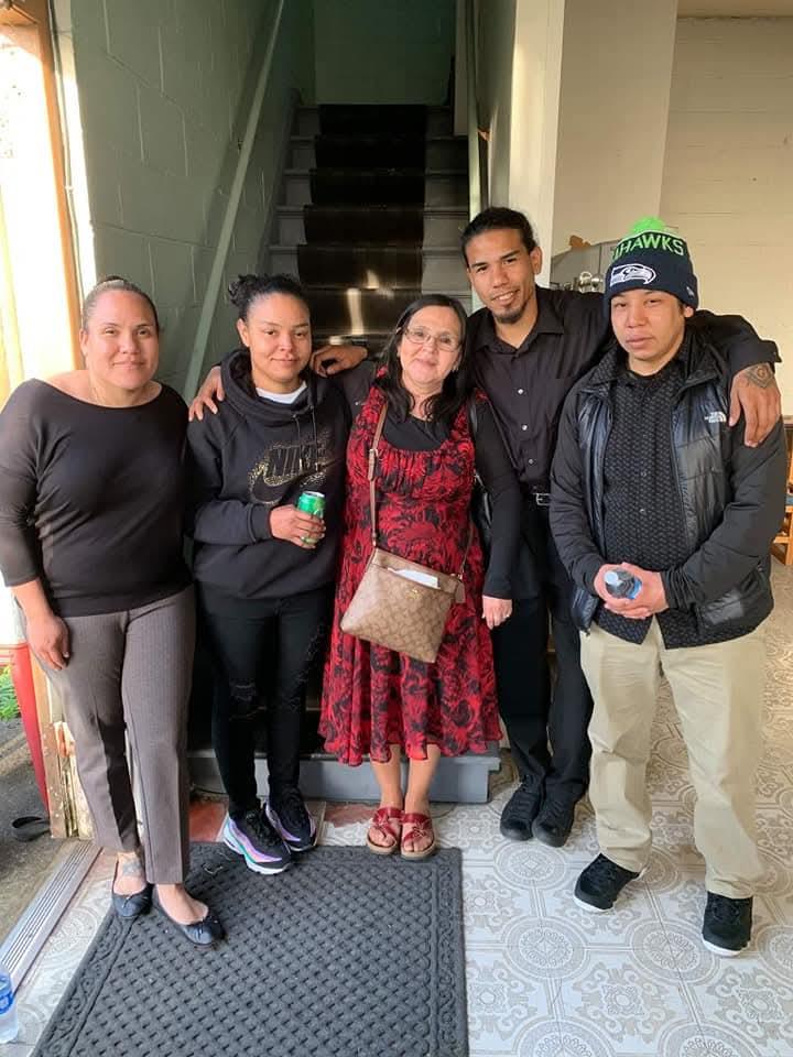 A group of five individuals stands together, showcasing warmth and connection in a comfortable home.