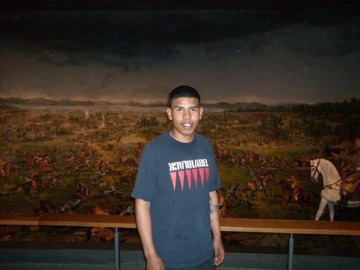 A person stands before a dramatic mural of a historical battle.