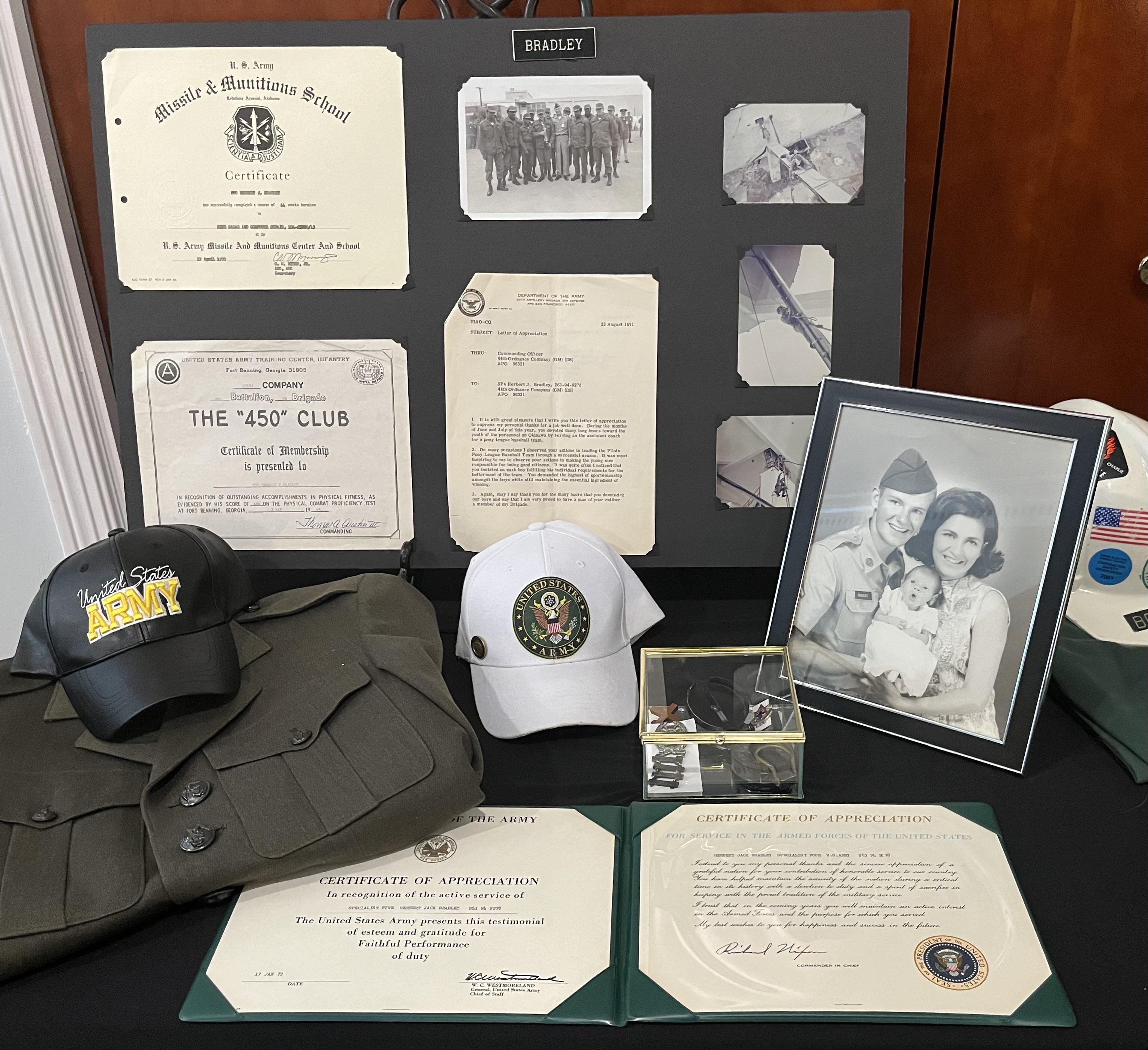 A detailed showcase of military artifacts including certificates, hats, and a family photograph.