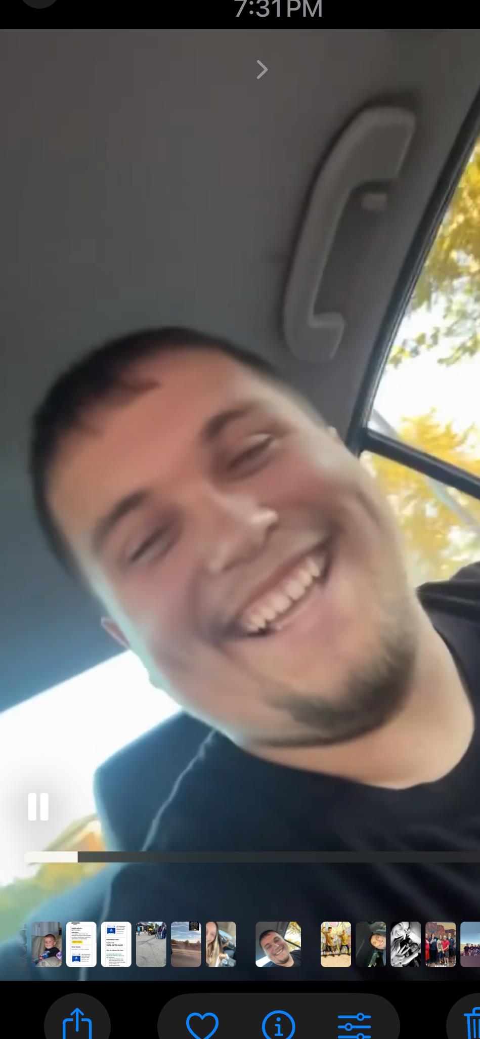 A cheerful man smiles widely while sitting in a car, experiencing a pleasant evening ambiance.