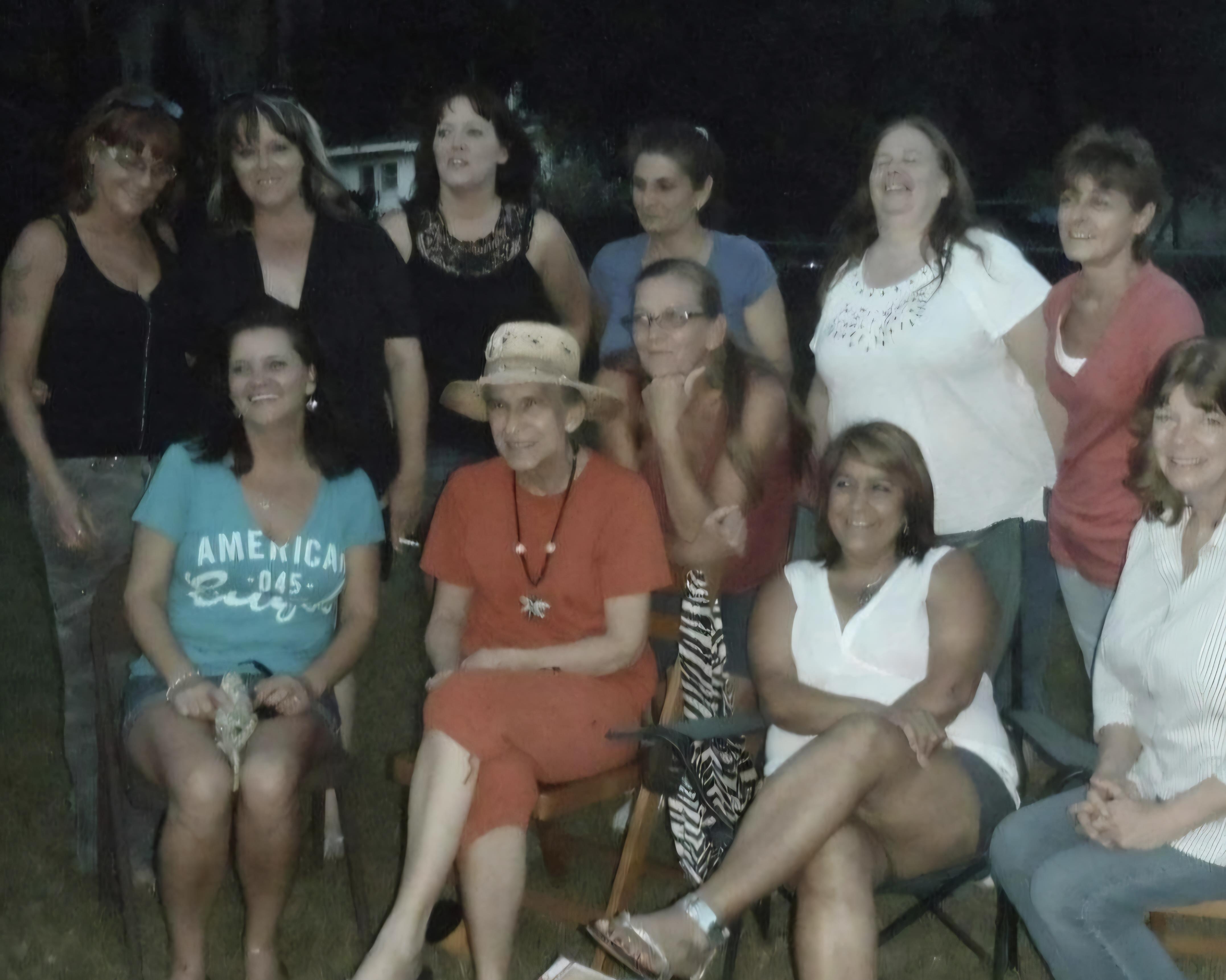 Women smile and share laughter during a summer evening gathering in a cozy backyard.