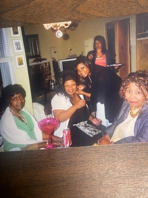 A group of women share laughs and food in a cozy living room setting during the afternoon.