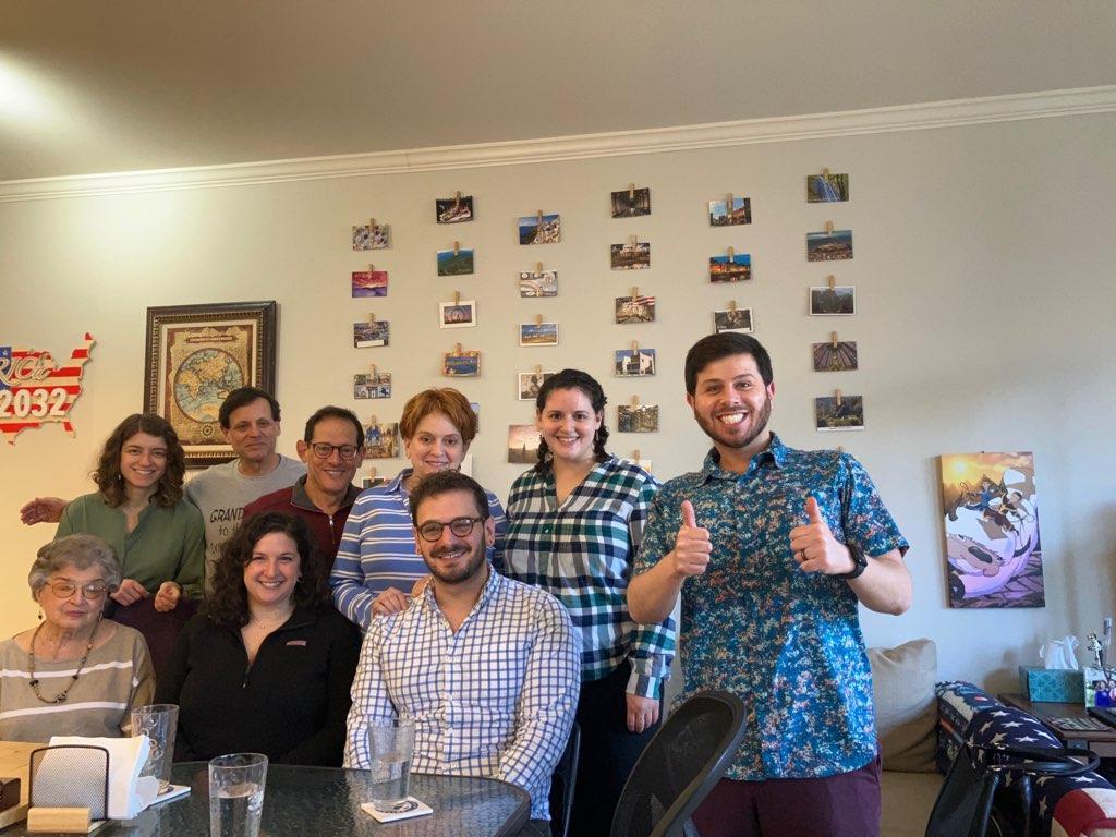 A group of diverse friends gathers, smiling and posing happily in a cafe's relaxed atmosphere.