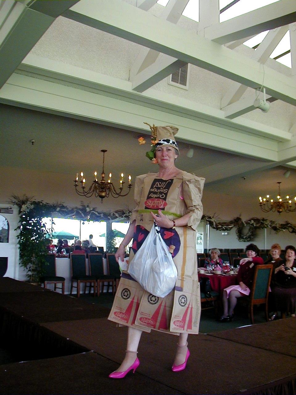 A model showcases a creative outfit made of recycled materials during a fashion event.
