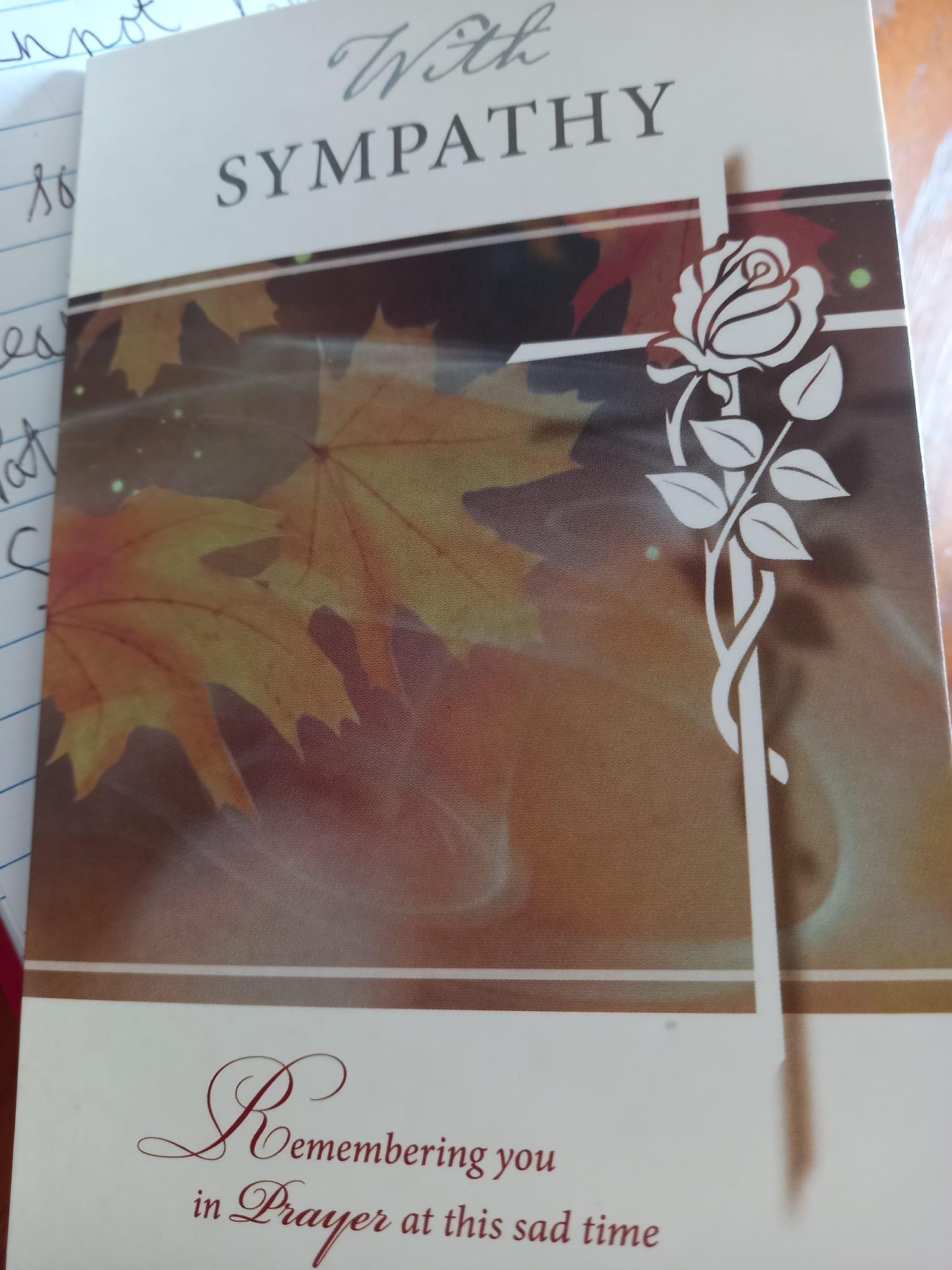 A beautifully designed sympathy card featuring autumn leaves and a rose, offering support.