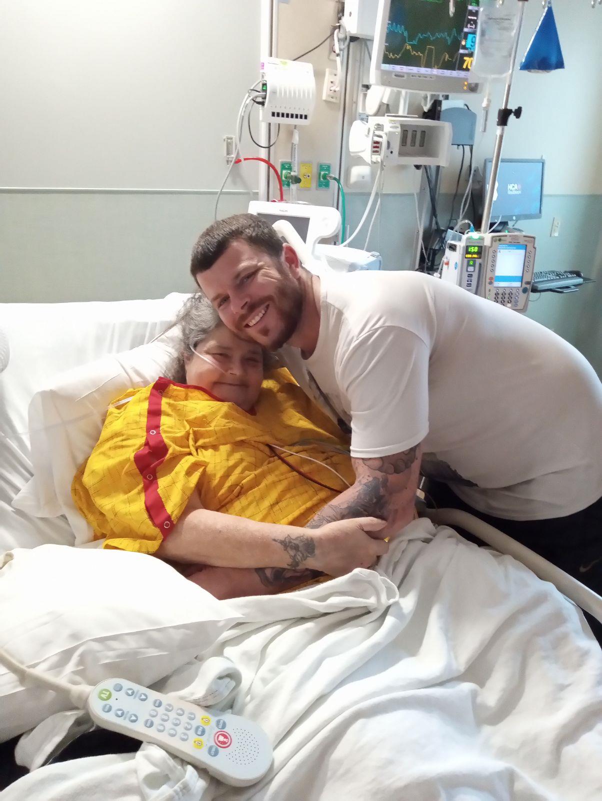 A joyful embrace between a patient and a family member inside a hospital room.