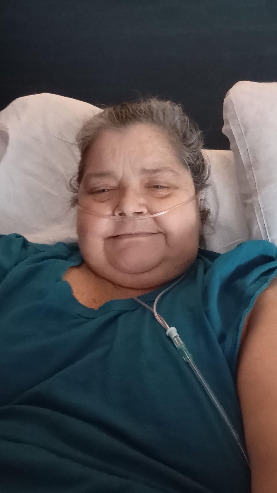 Person in a blue shirt relaxes in bed, receiving oxygen therapy peacefully.