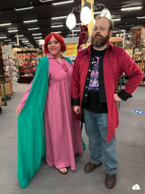 Two individuals enjoy their time in elaborate costumes at a lively convention during the weekend.