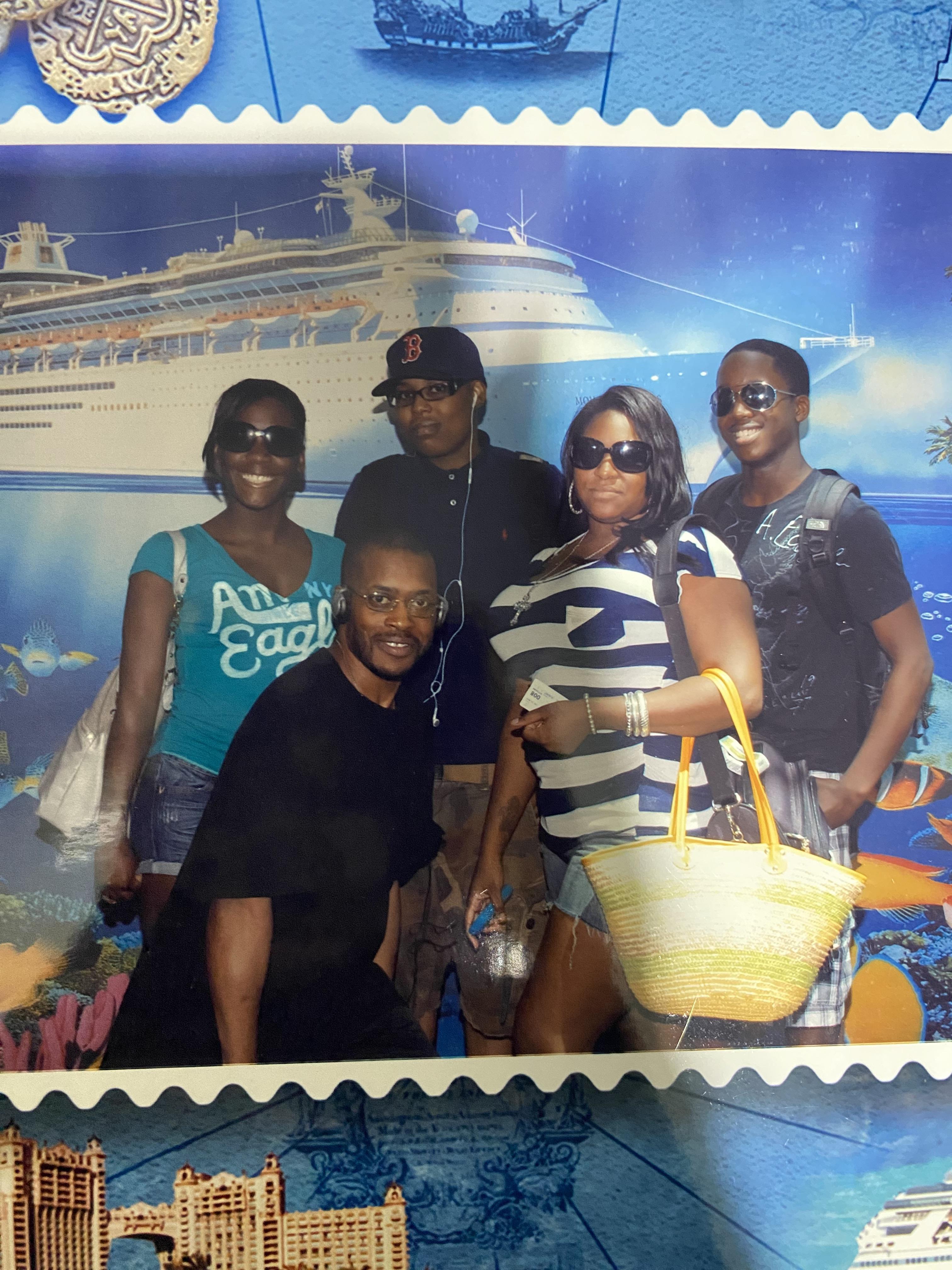 Friends gather excitedly, showcasing smiles in front of a cruise ship in a tropical setting.
