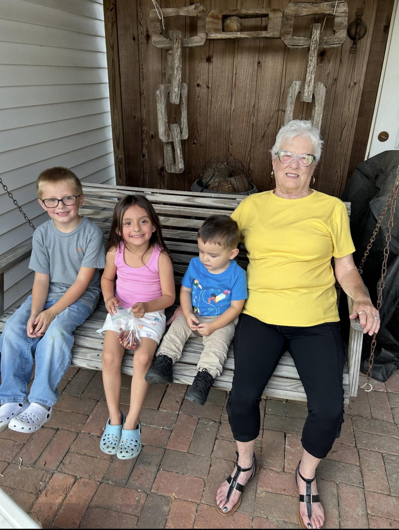Four family members enjoy time together on a wooden swing, smiling and sharing moments.