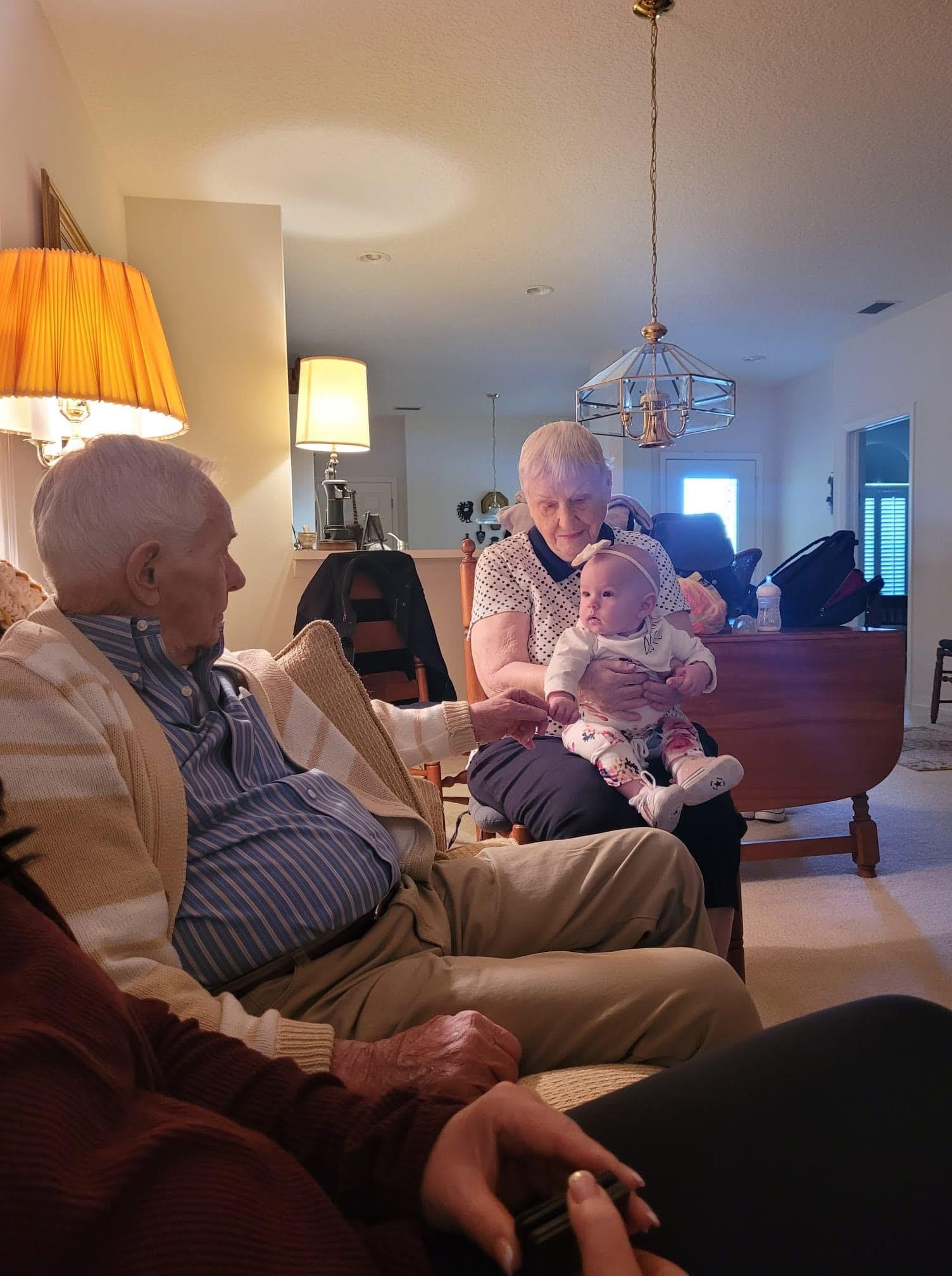 Grandparents engage lovingly with their grandchild in a cozy living room setting.