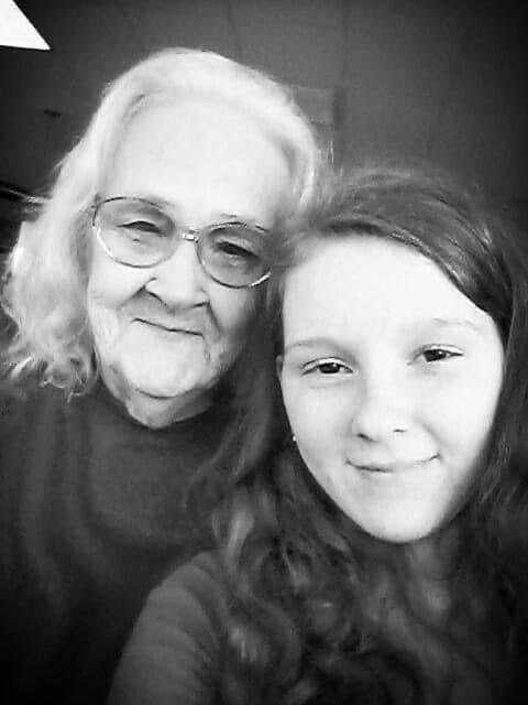 A young girl smiles alongside her grandmother, enjoying a heartfelt moment together at dusk.