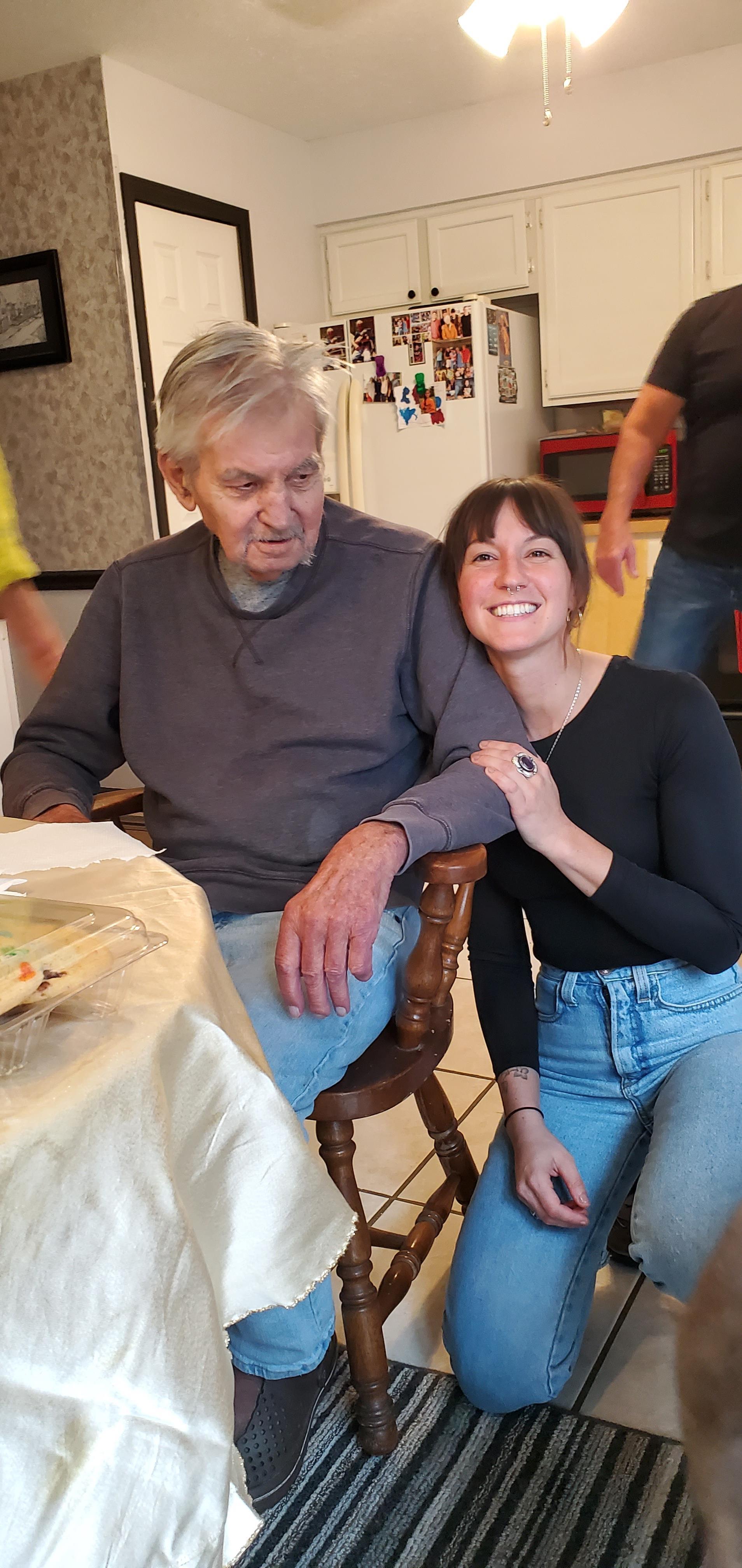 An elderly man and a young woman enjoy quality time together at a family gathering in a kitchen.