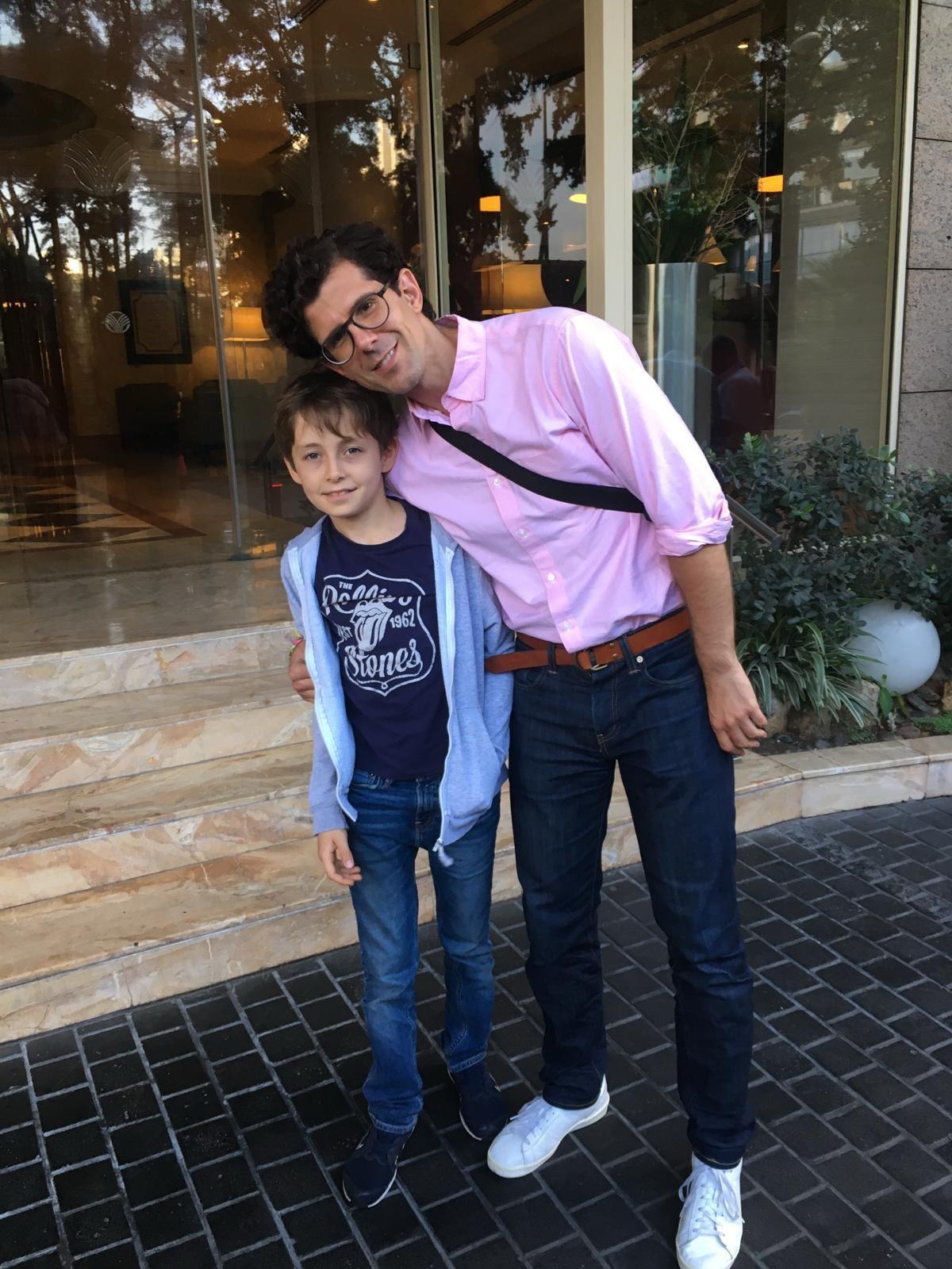 Two people stand together outside a hotel, smiling and enjoying each other's company.
