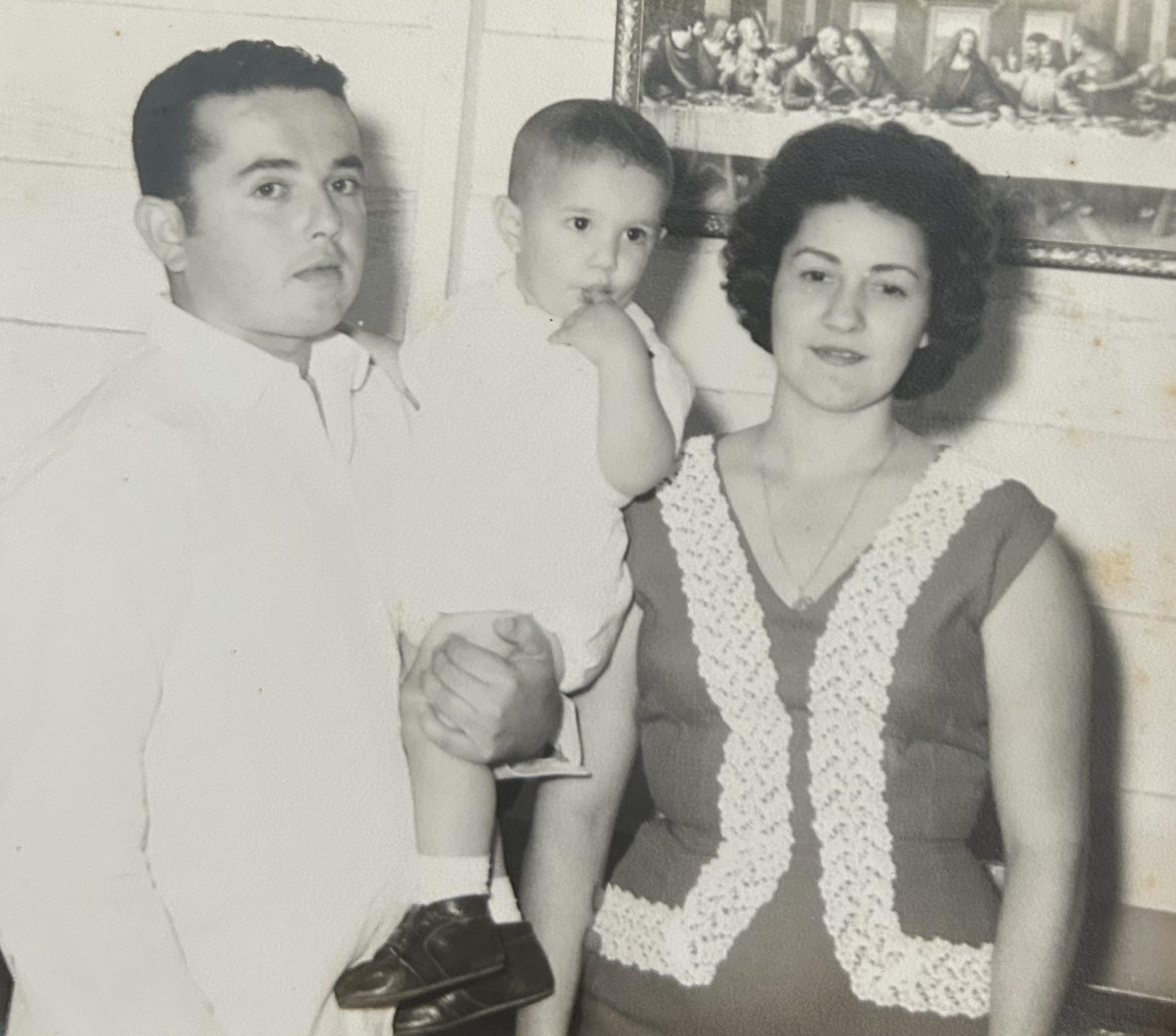 A couple stands together with their toddler in a cozy living room, capturing a loving family moment.