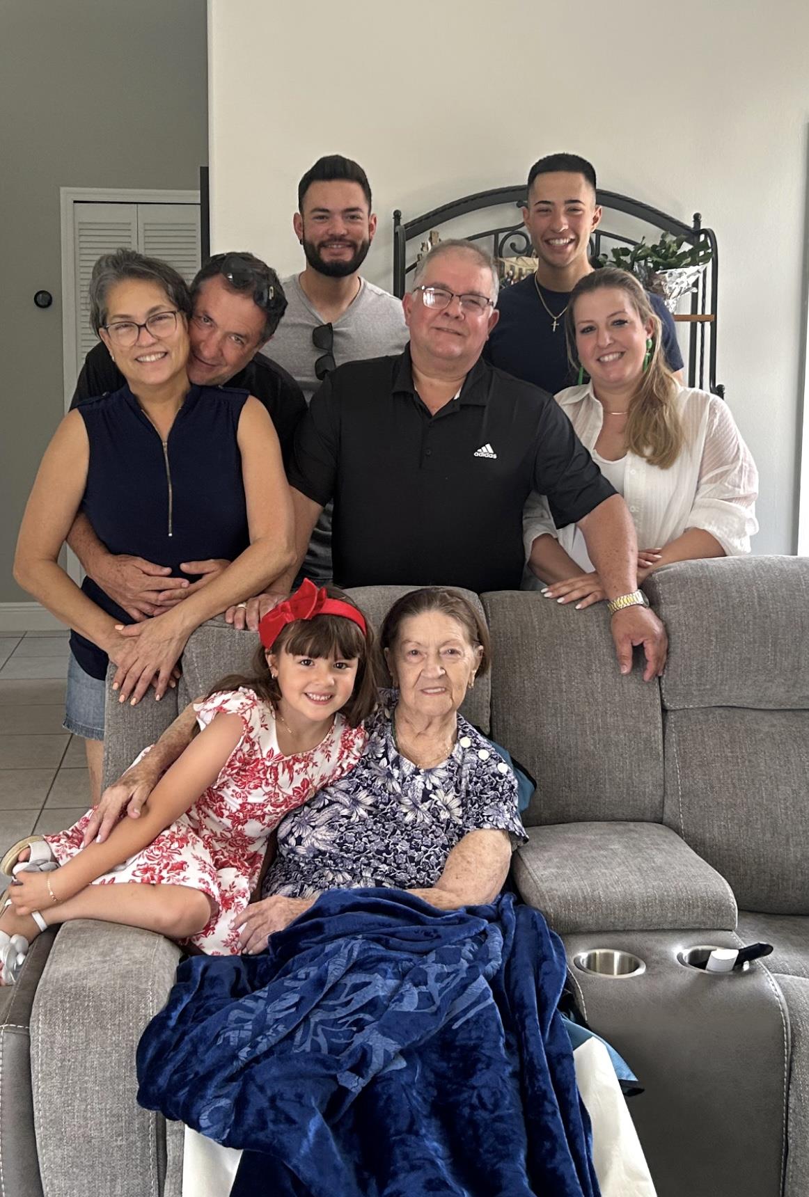 Family gathers with grandmother, sharing smiles and love in a cozy living room.