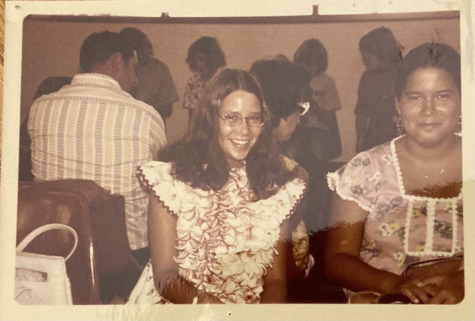 A joyful woman in a floral dress enjoys a lively social gathering with friends.