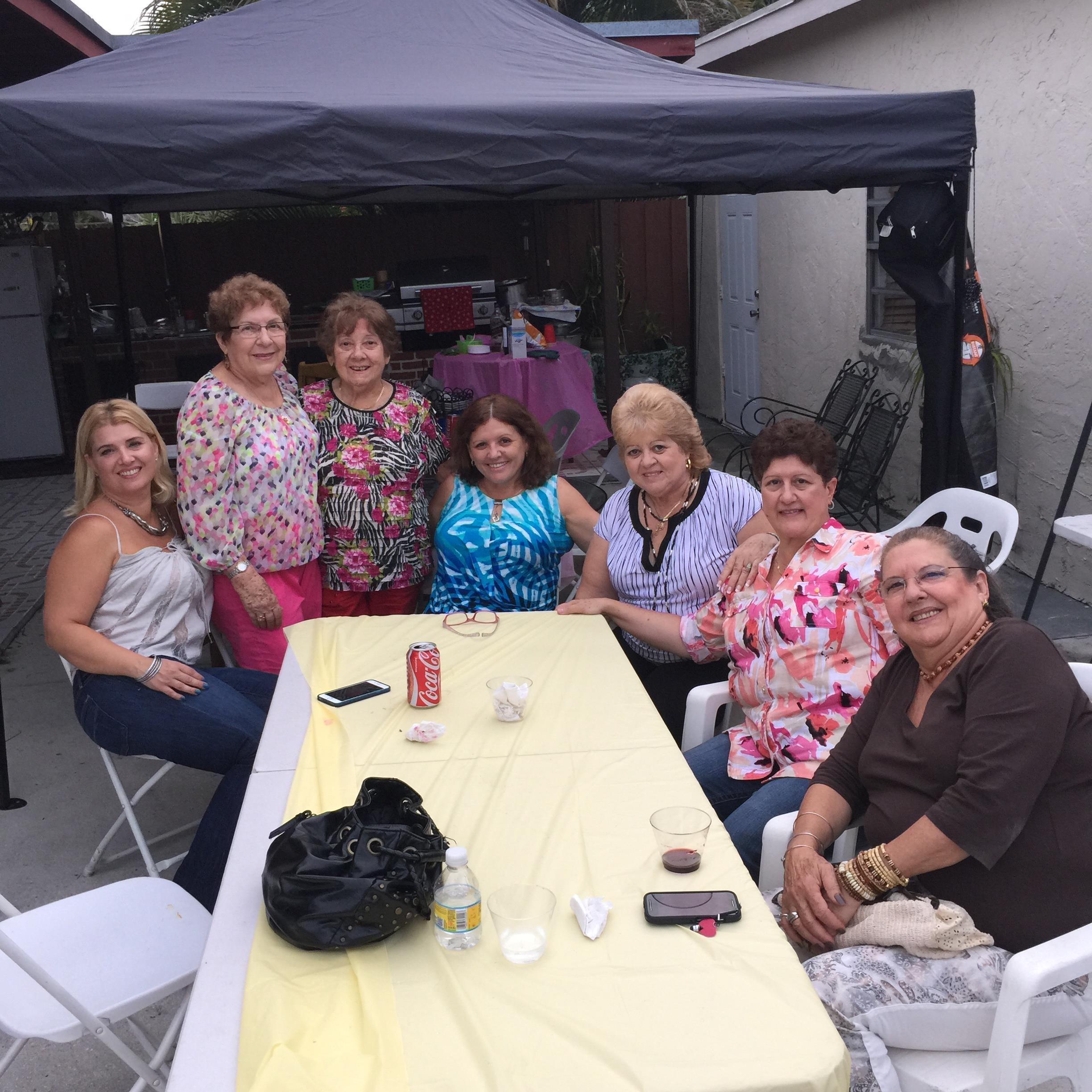 A group of friends sits around a table, celebrating together in a cheerful outdoor atmosphere.