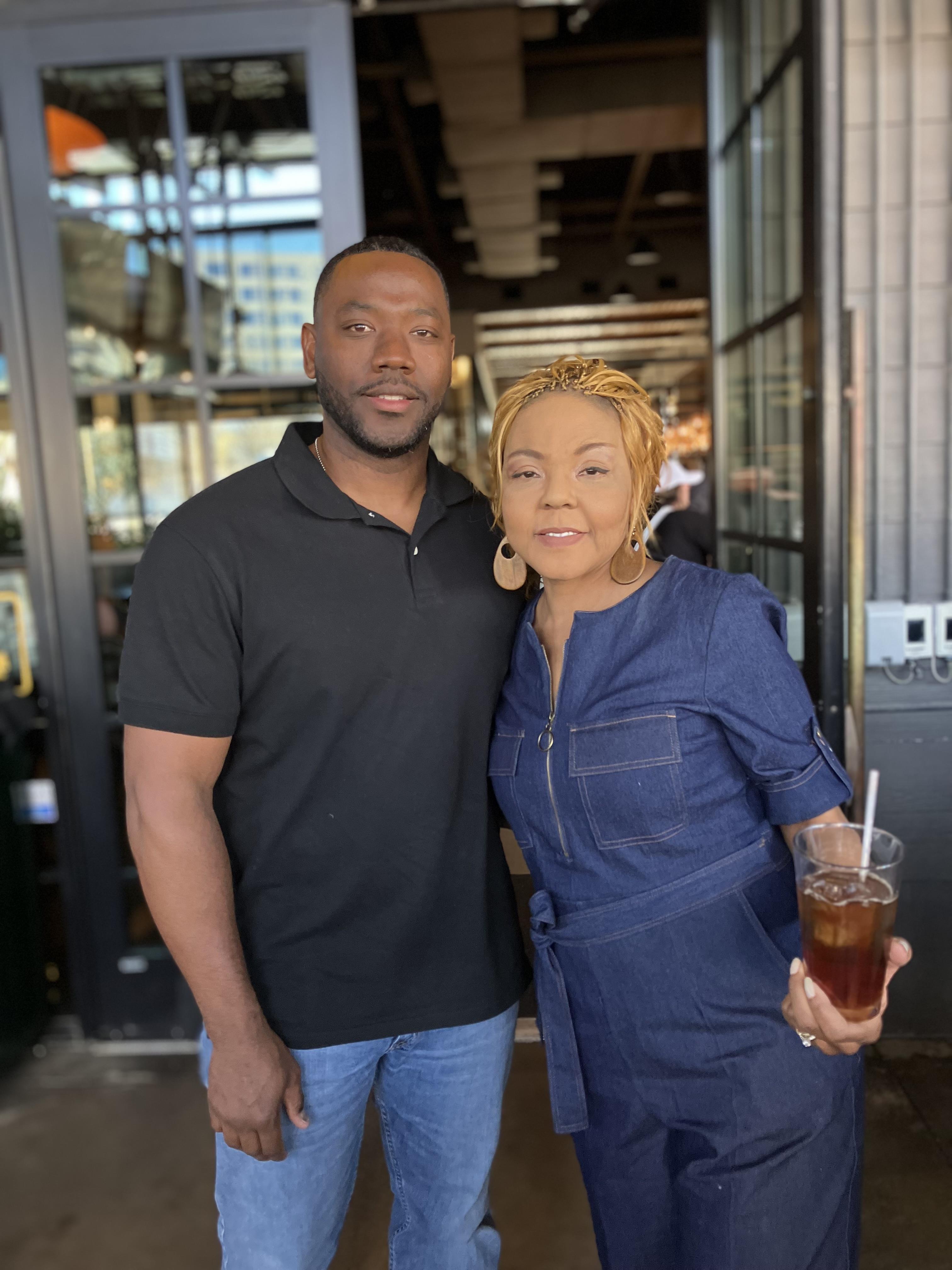Two individuals pose happily inside a trendy restaurant, enjoying a joyful moment together.