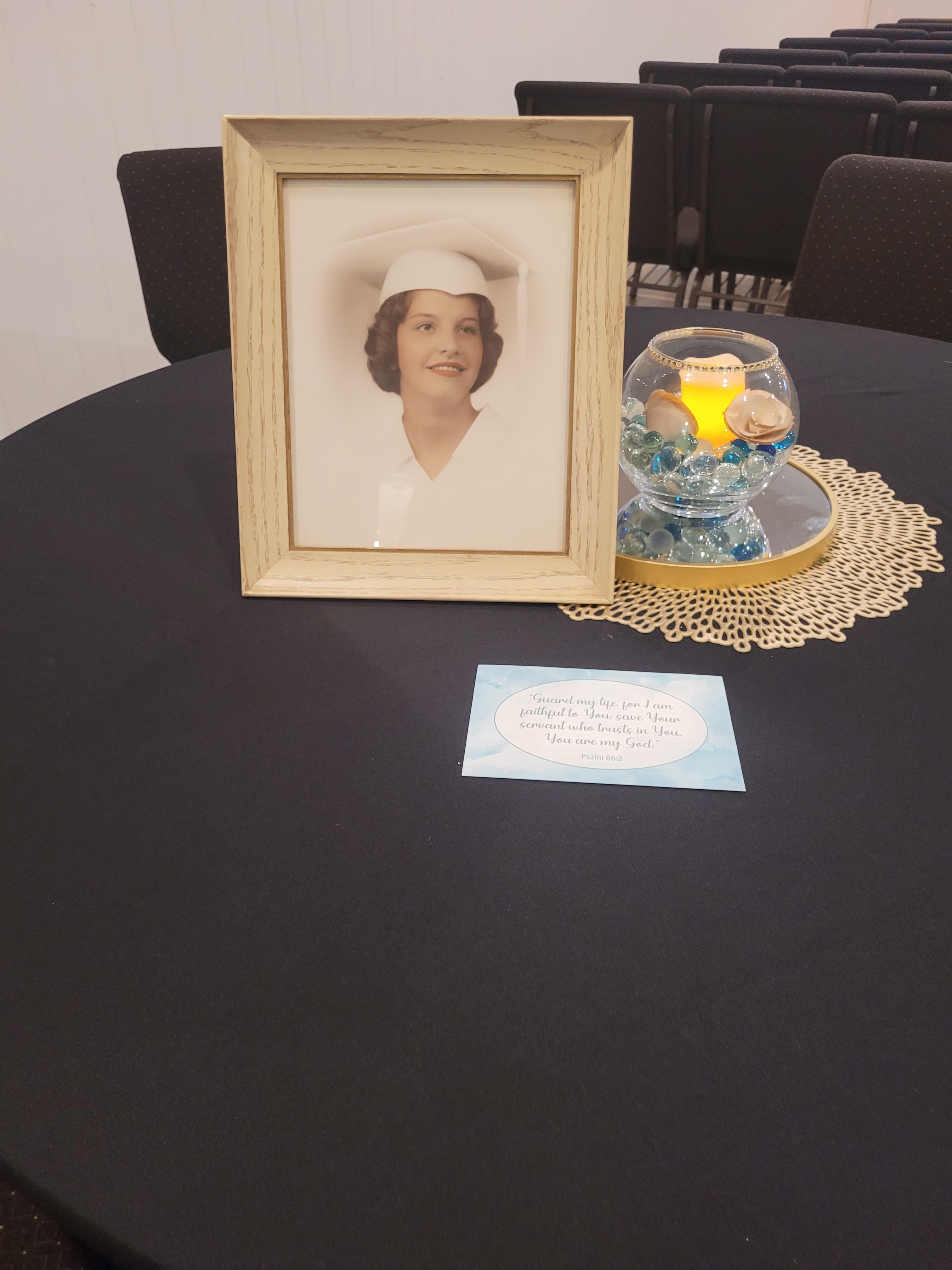A framed vintage portrait displays a smiling woman with a hat, set on a decorated table.