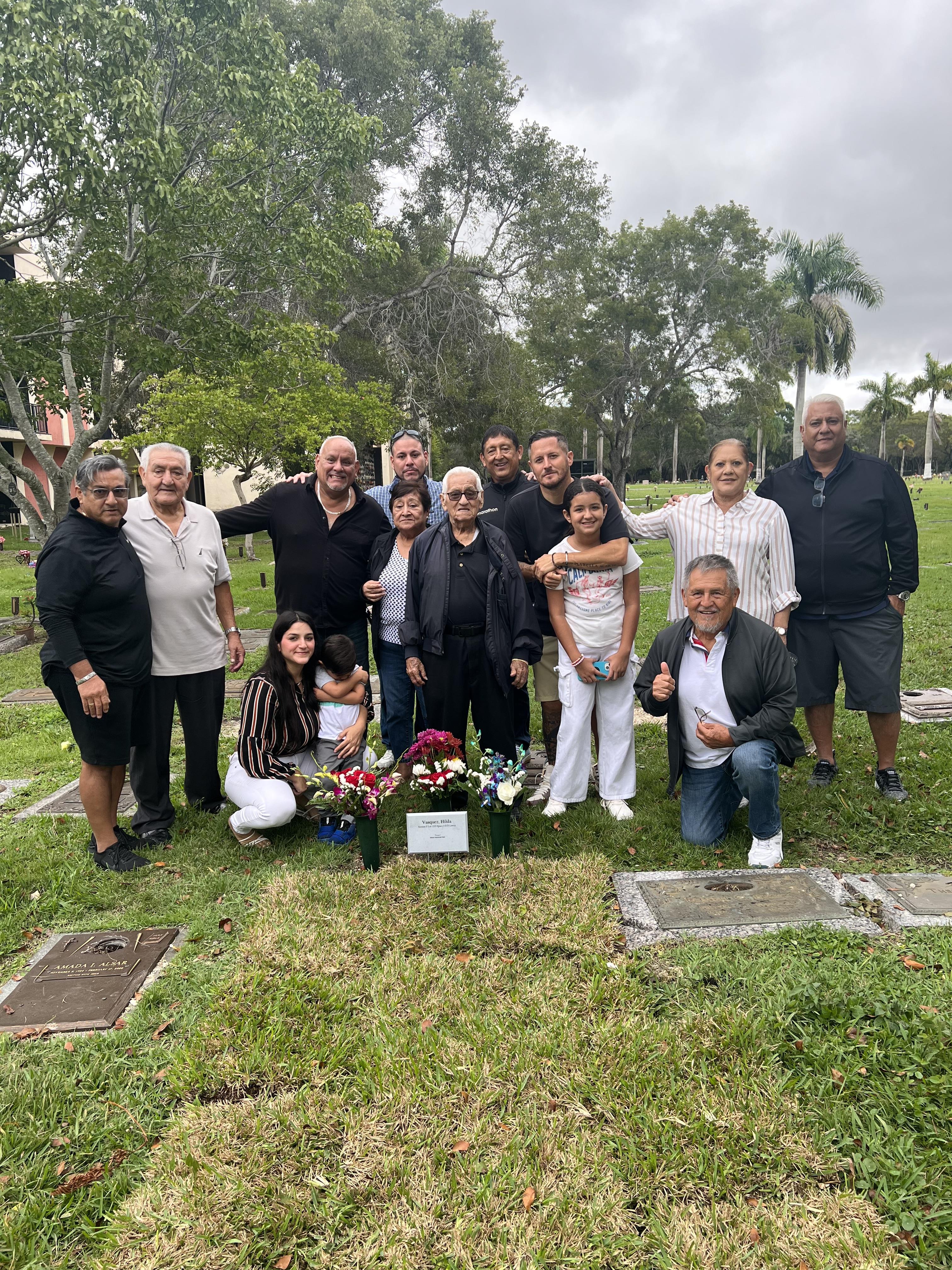 Relatives unite at cemetery, paying respects with flowers and shared memories in a peaceful setting.