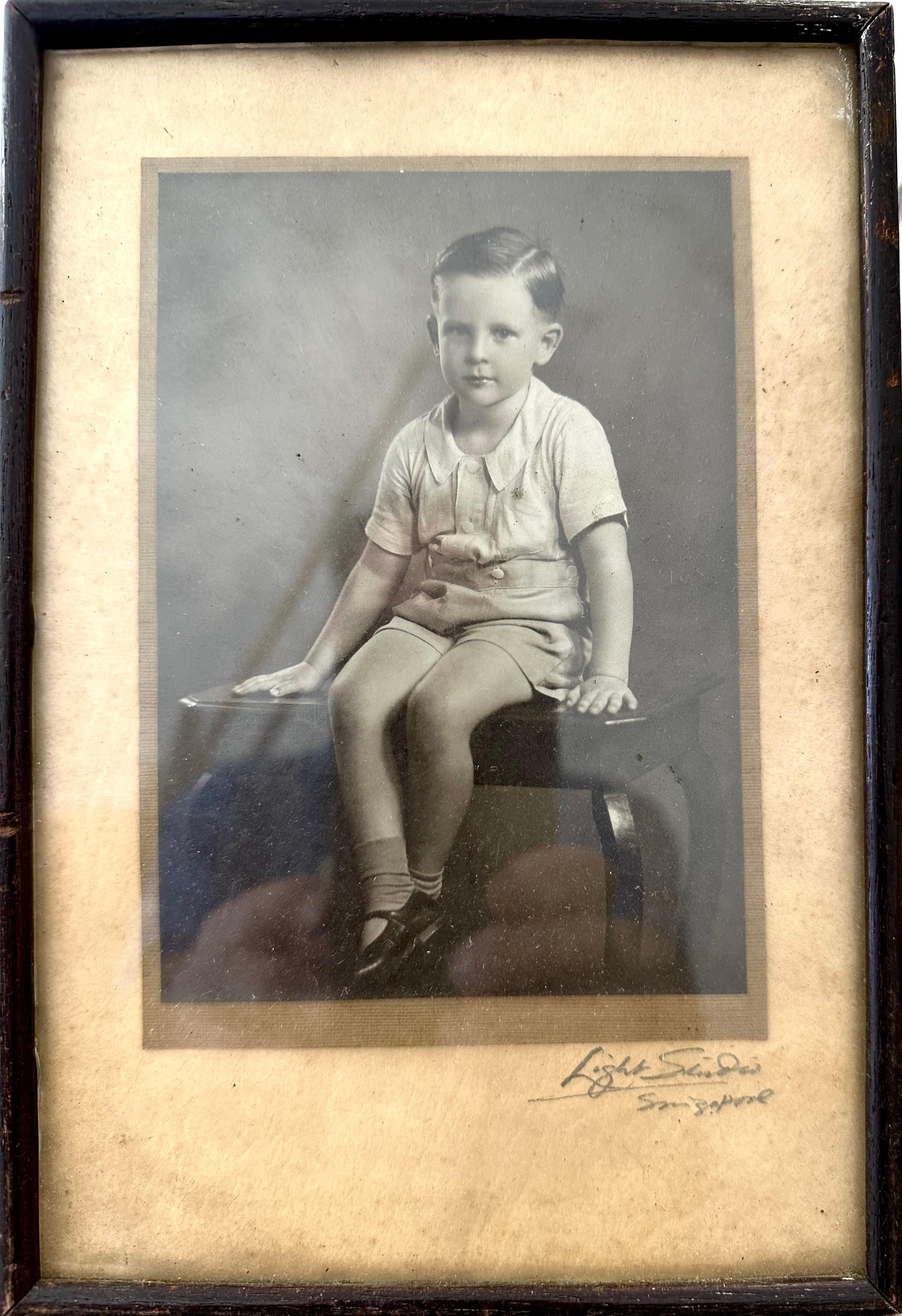 A young boy sits on a stool in shorts, showcasing a playful expression of childhood innocence.