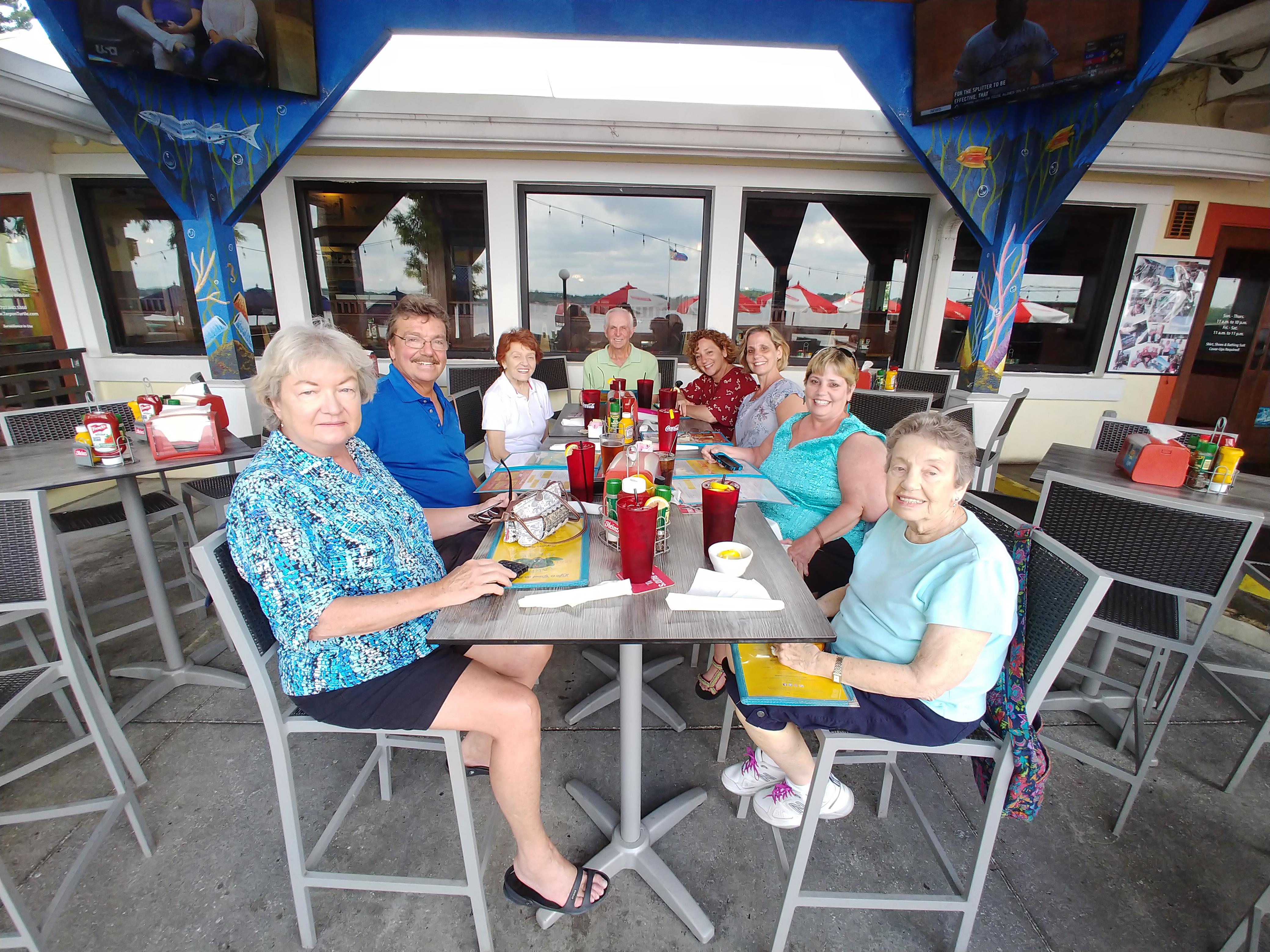 Friends gather at an outdoor restaurant, sharing laughs and enjoying lunch together.