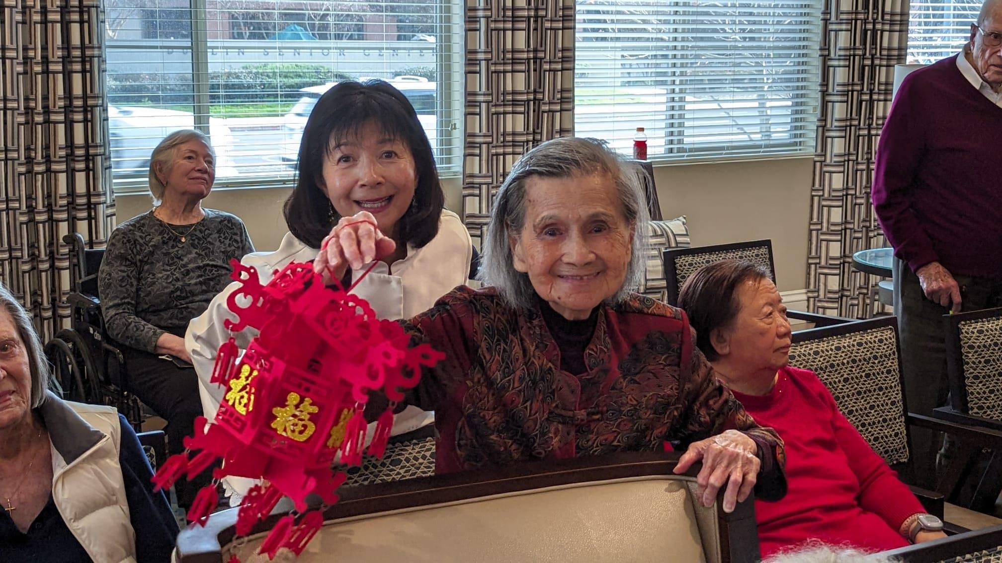 Residents partake in a joyful celebration, holding colorful lanterns and sharing smiles together.