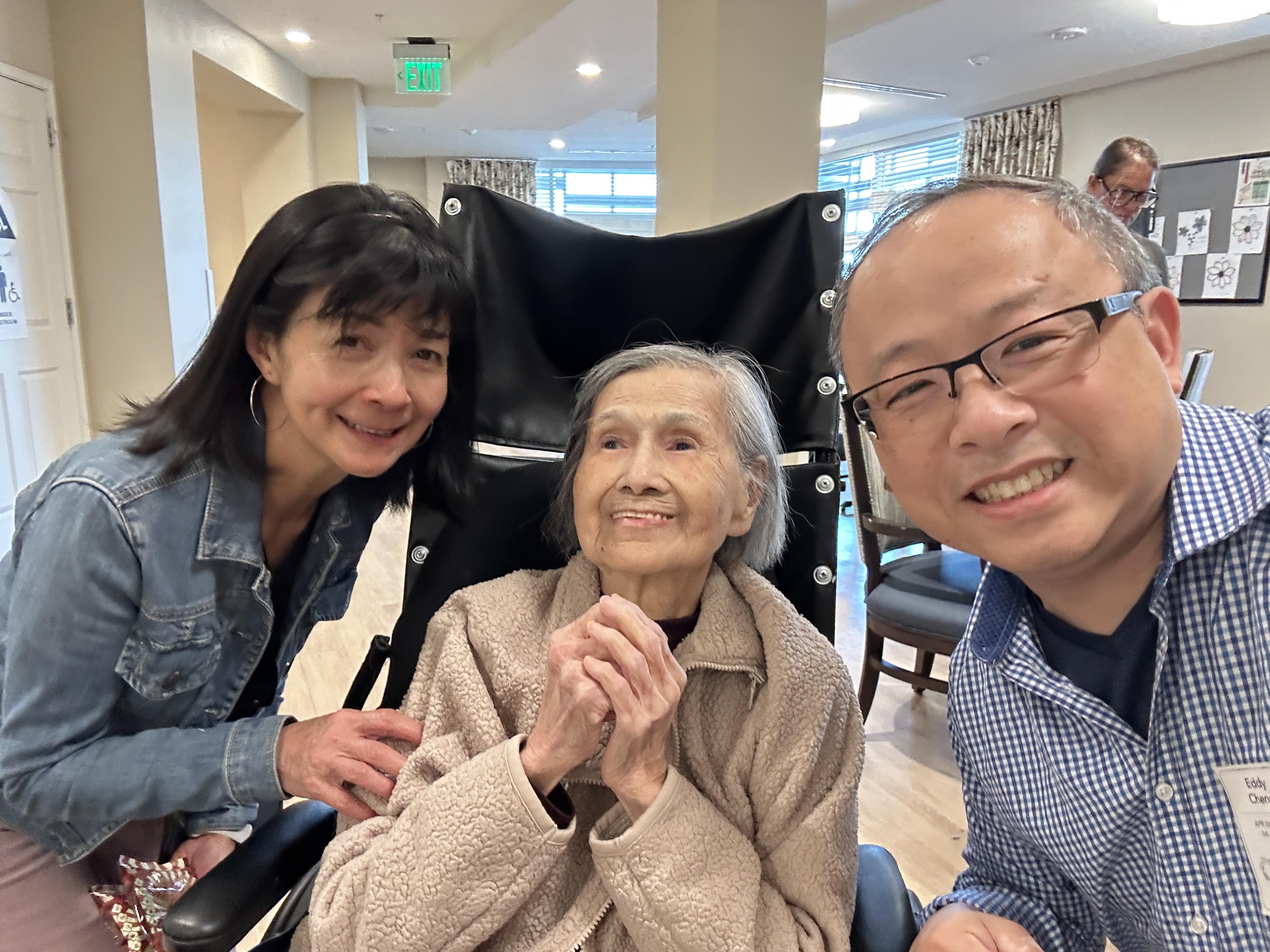 Family members warmly engage with an elderly woman during a visit at a care center.