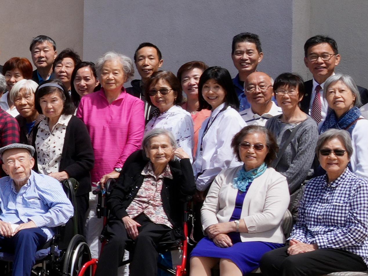 Seniors pose happily at a community center, celebrating friendship and life in spring.