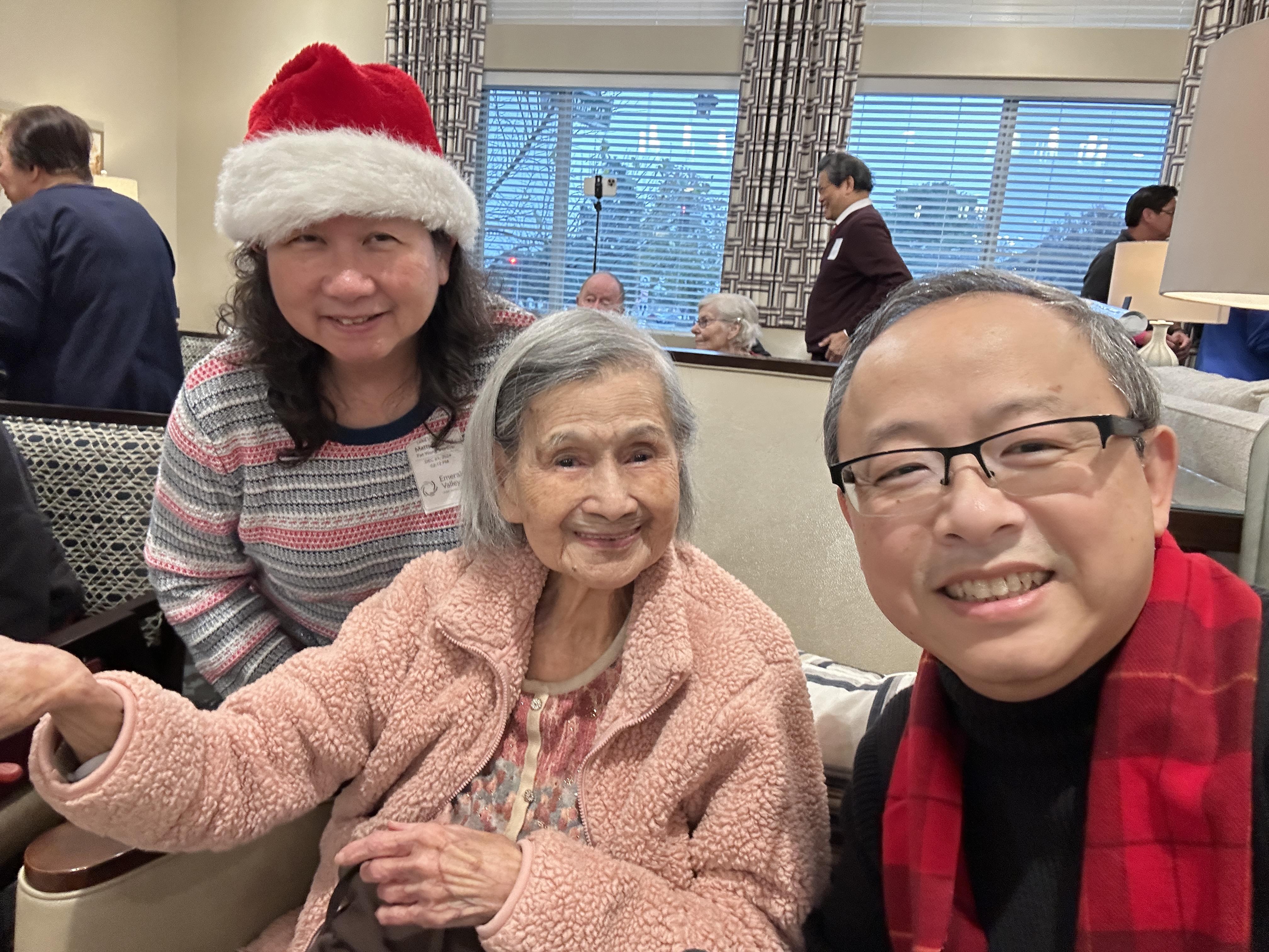Smiling faces of a woman in a festive hat with two seniors, enjoying a cheerful gathering.