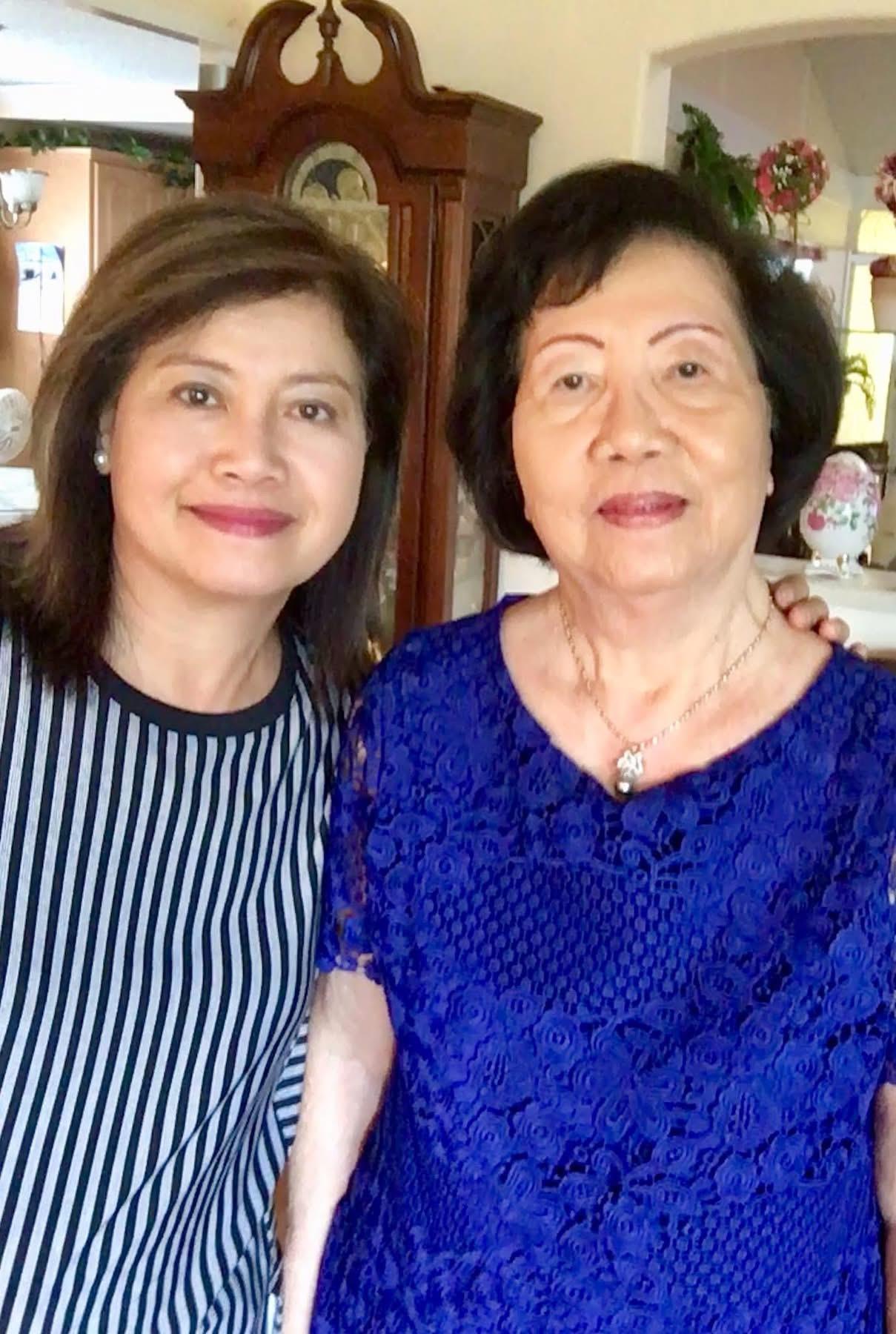 Two women smiling warmly together at home, enjoying a family gathering on a sunny afternoon.