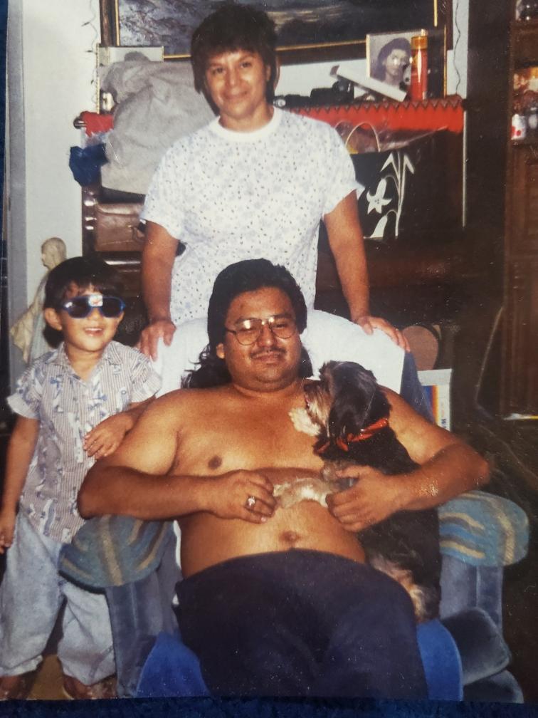 A man relaxes in a chair with a dog while a woman and child share joyful moments nearby.