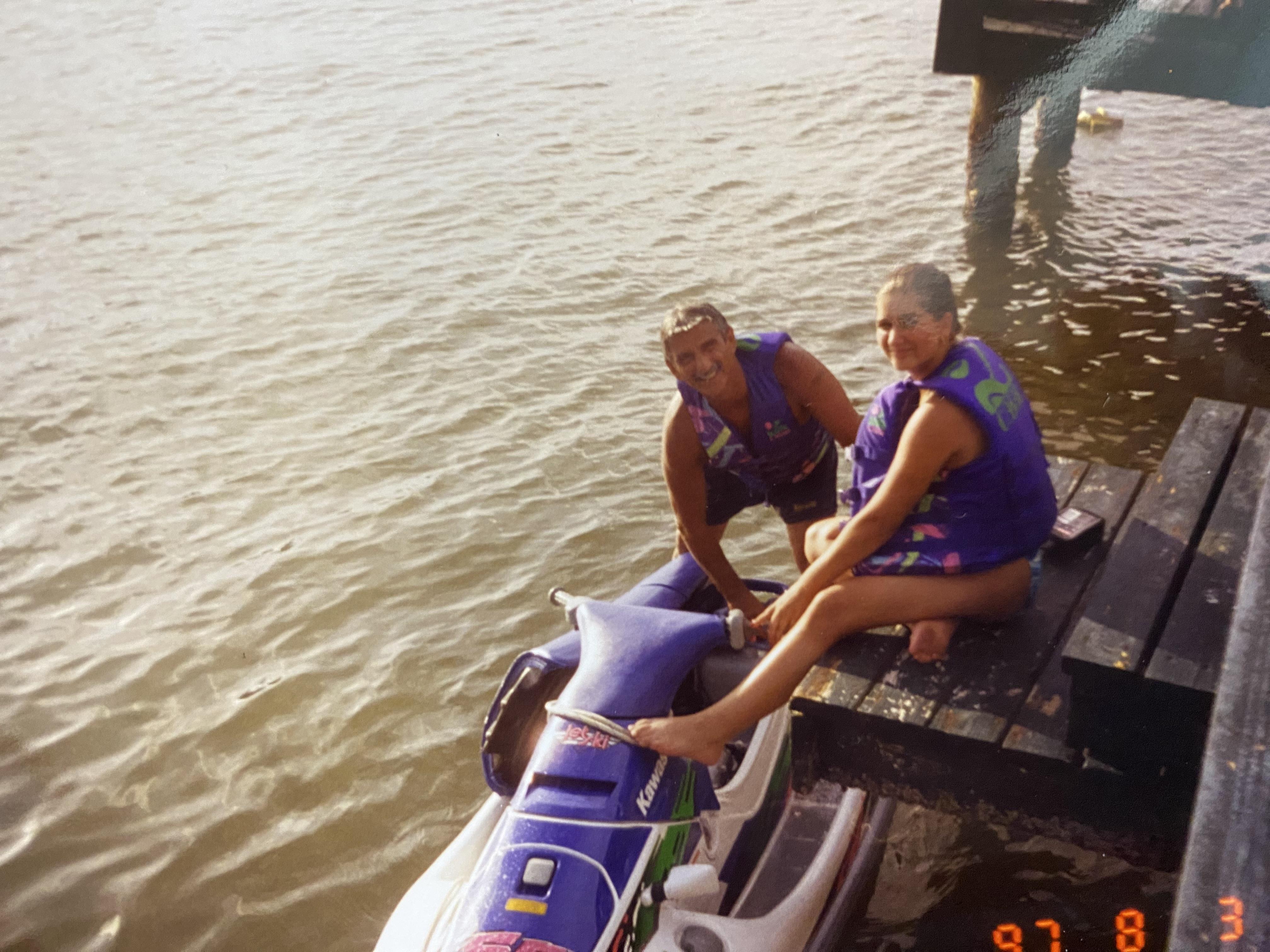 Friends prepare to ride a jet ski on calm waters during a sunny afternoon at the dock.