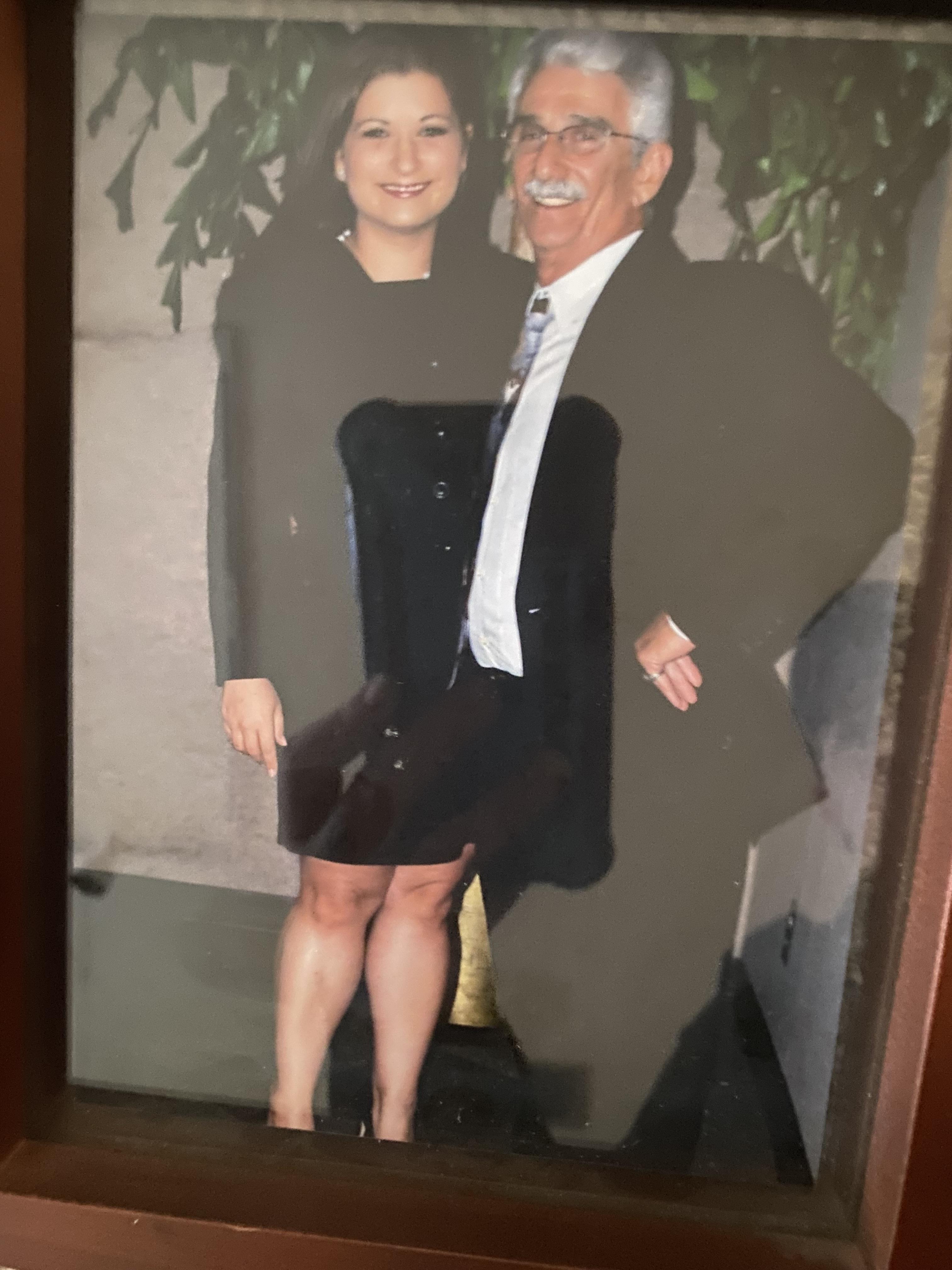 A happy couple smiles together at a formal gathering, dressed elegantly indoors.