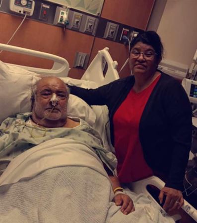 A woman standing next to a man in a hospital bed