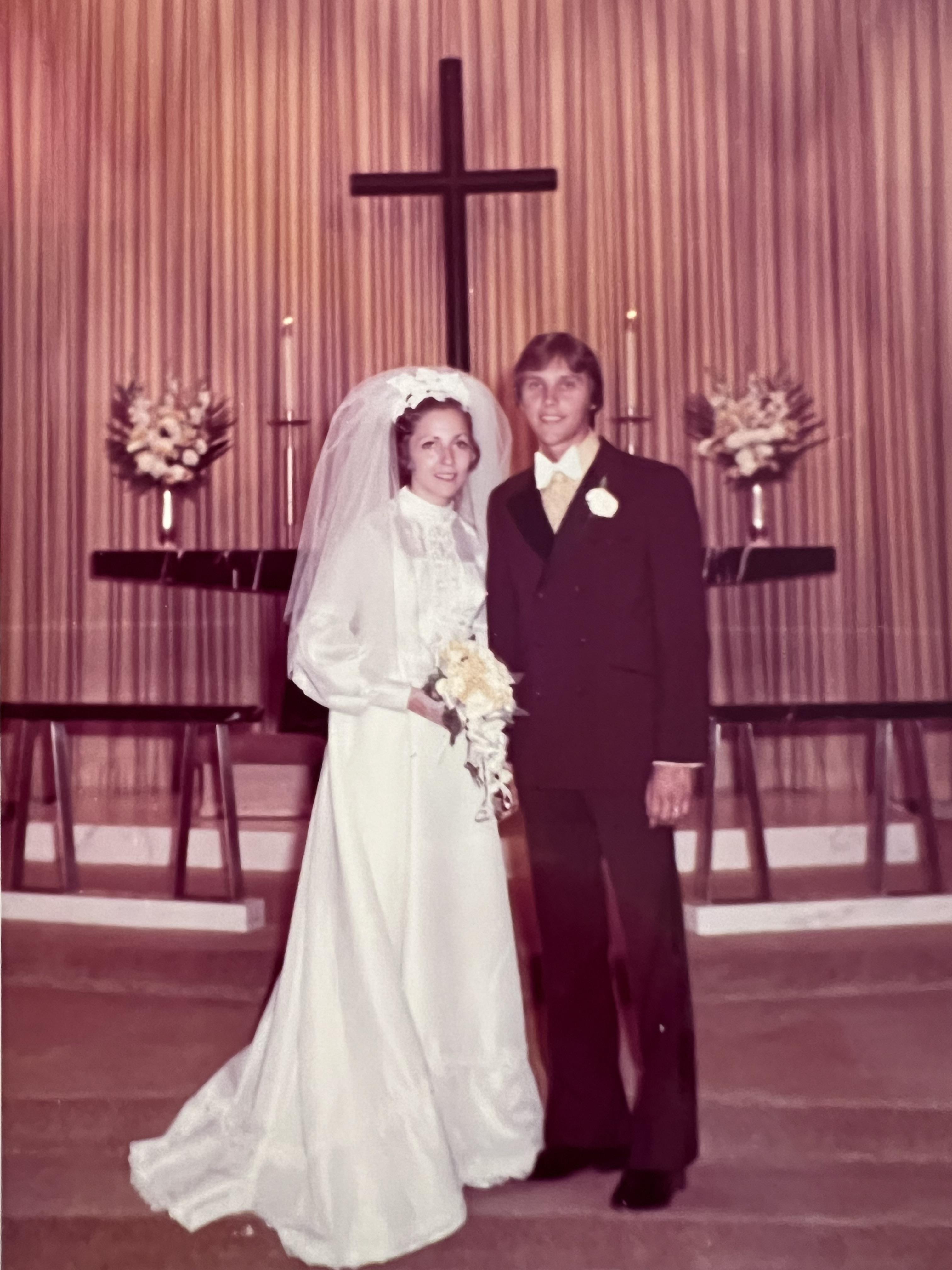 A couple stands together at their wedding ceremony in a chapel, radiating joy and love.