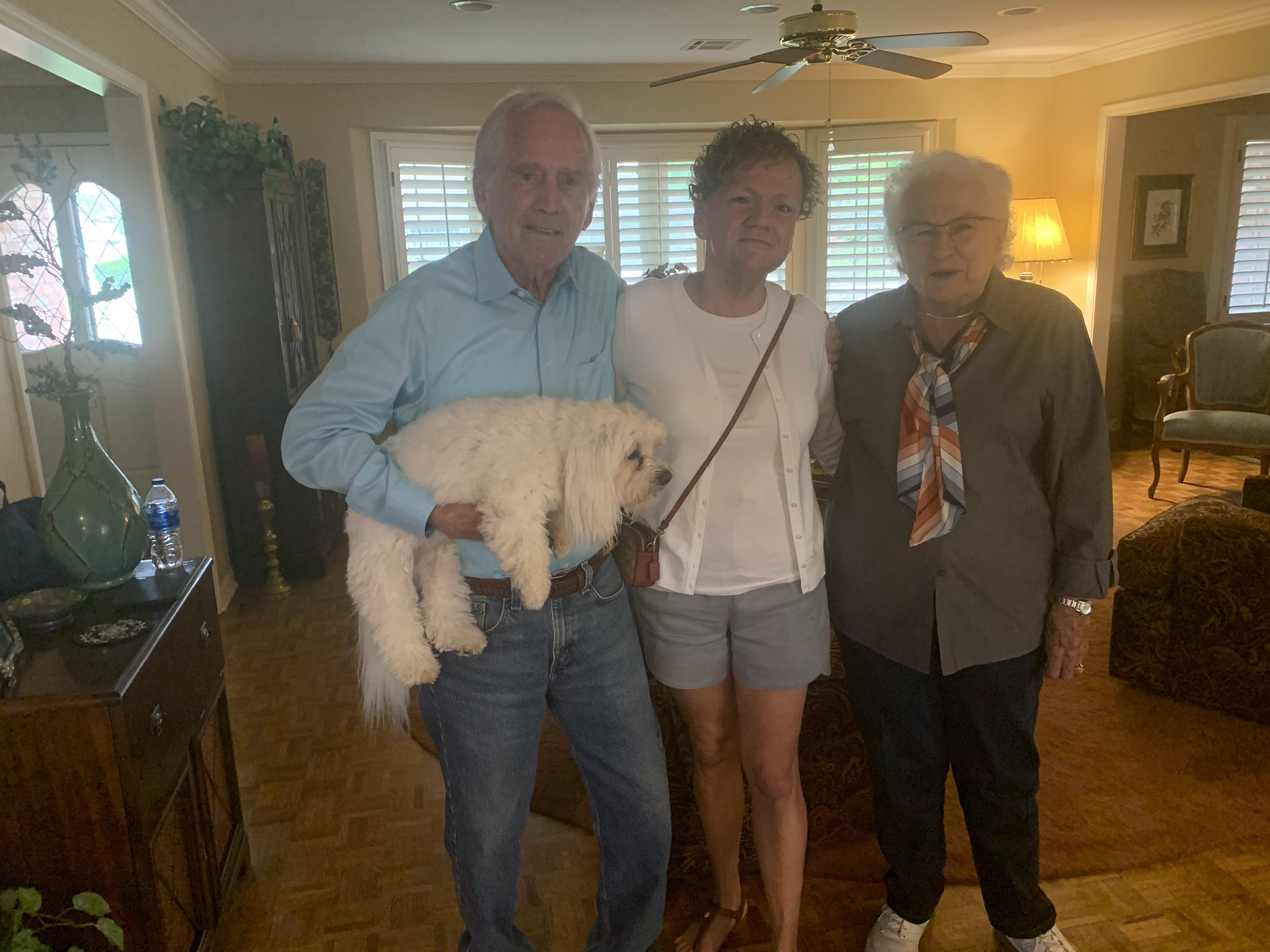 A family enjoys time together in a warm, inviting living room while holding a small dog.