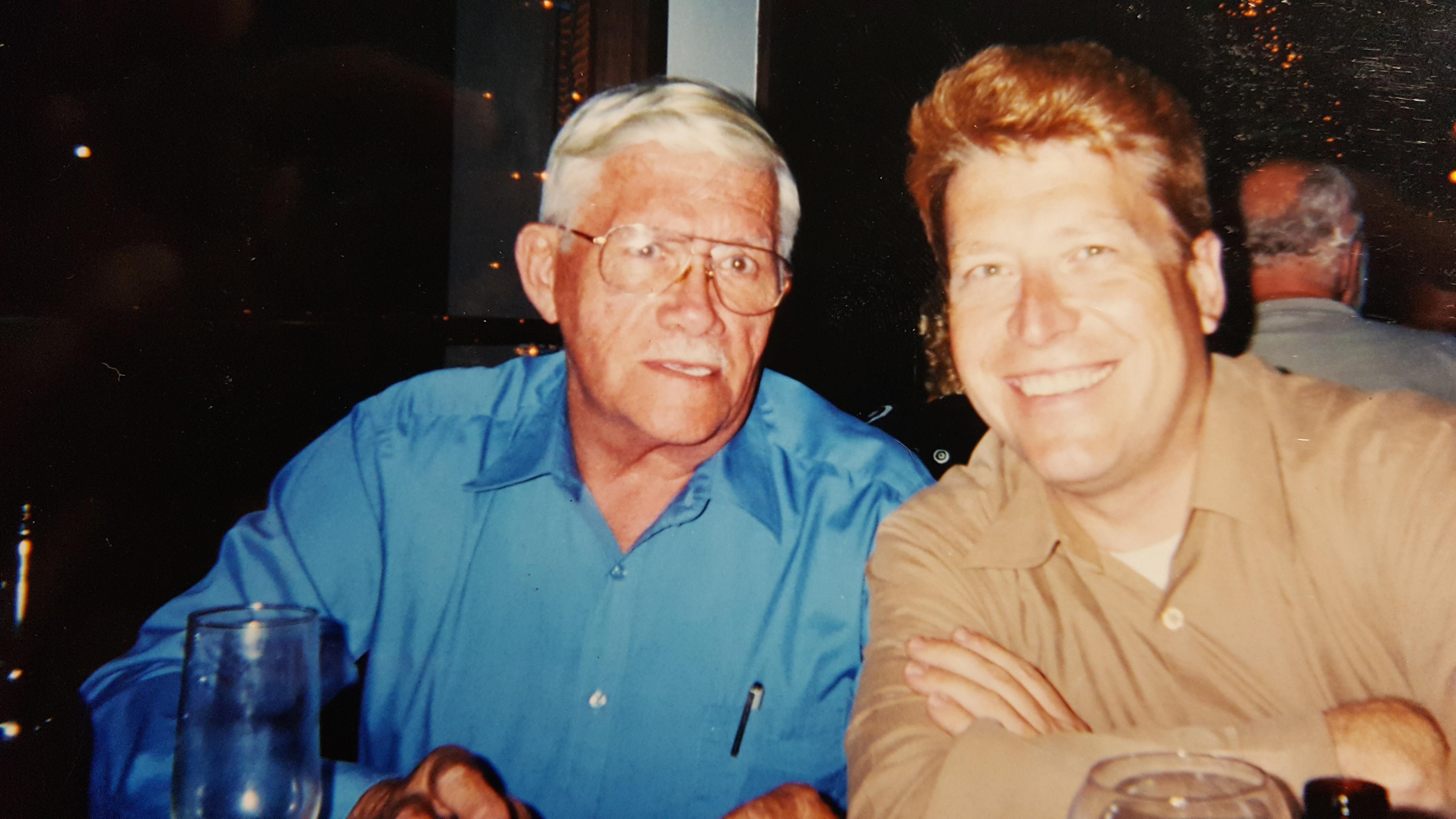 Two men share a cheerful moment at a restaurant, smiling and engaging in conversation.