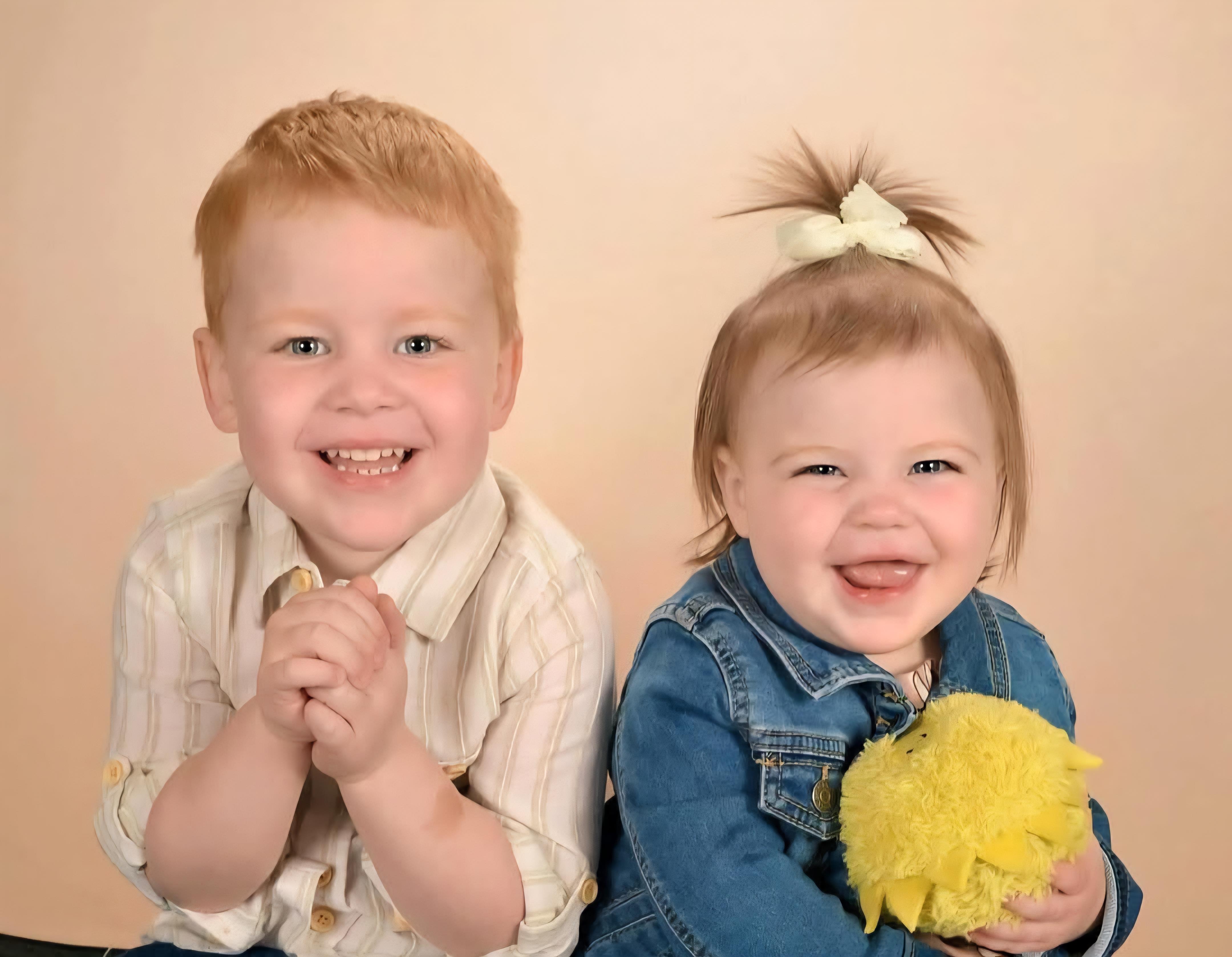 Two children express happiness and joy while posing together, highlighting their close relationship.