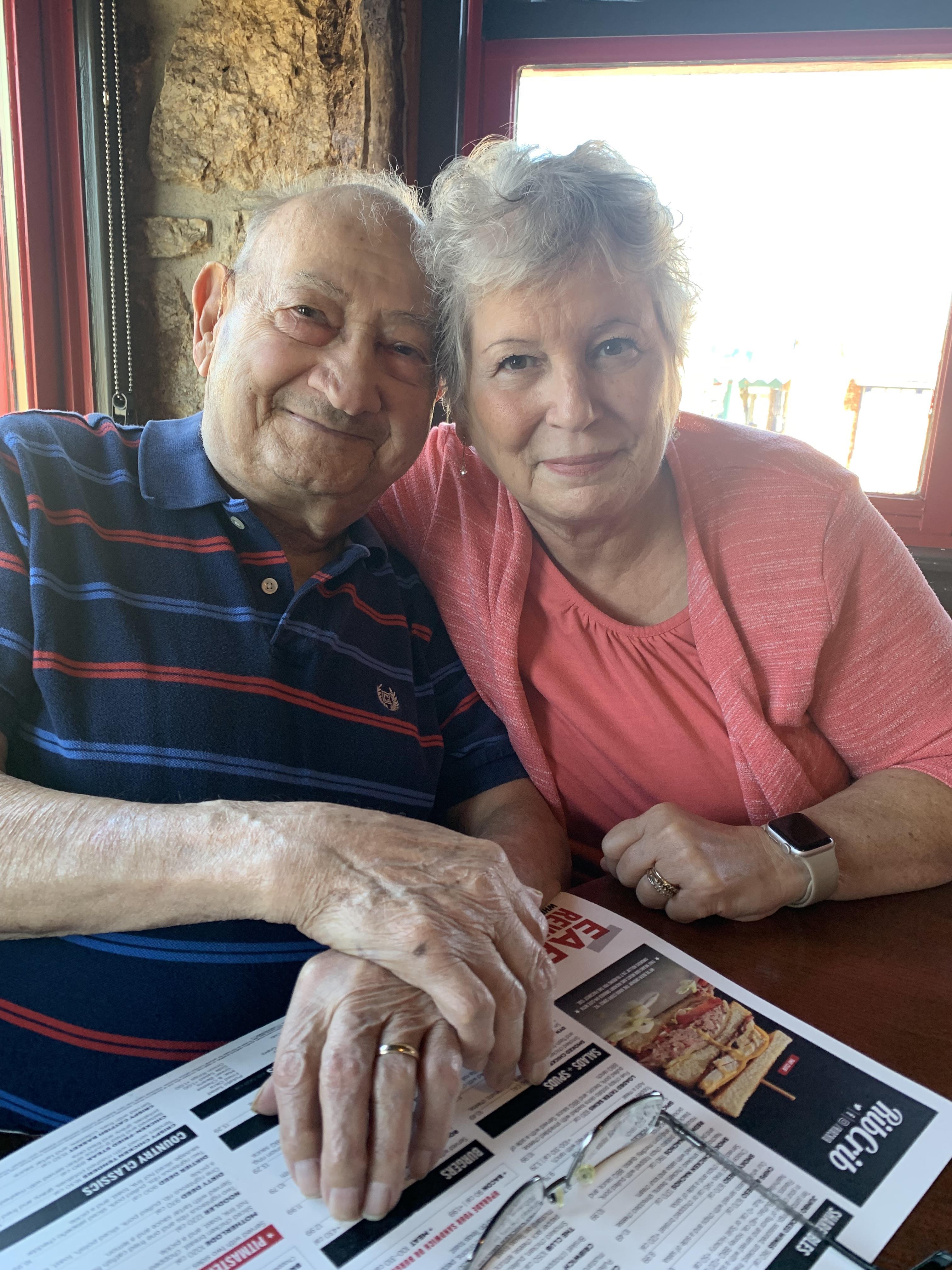 Two smiling seniors share a moment while seated at a table, enjoying their lunch date.