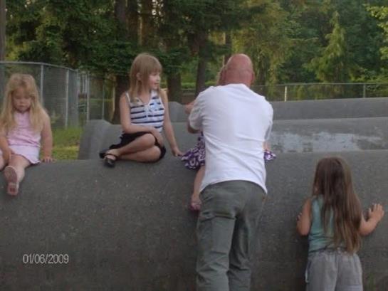 Group of children enjoying outdoor playtime on concrete structures while an adult watches them.