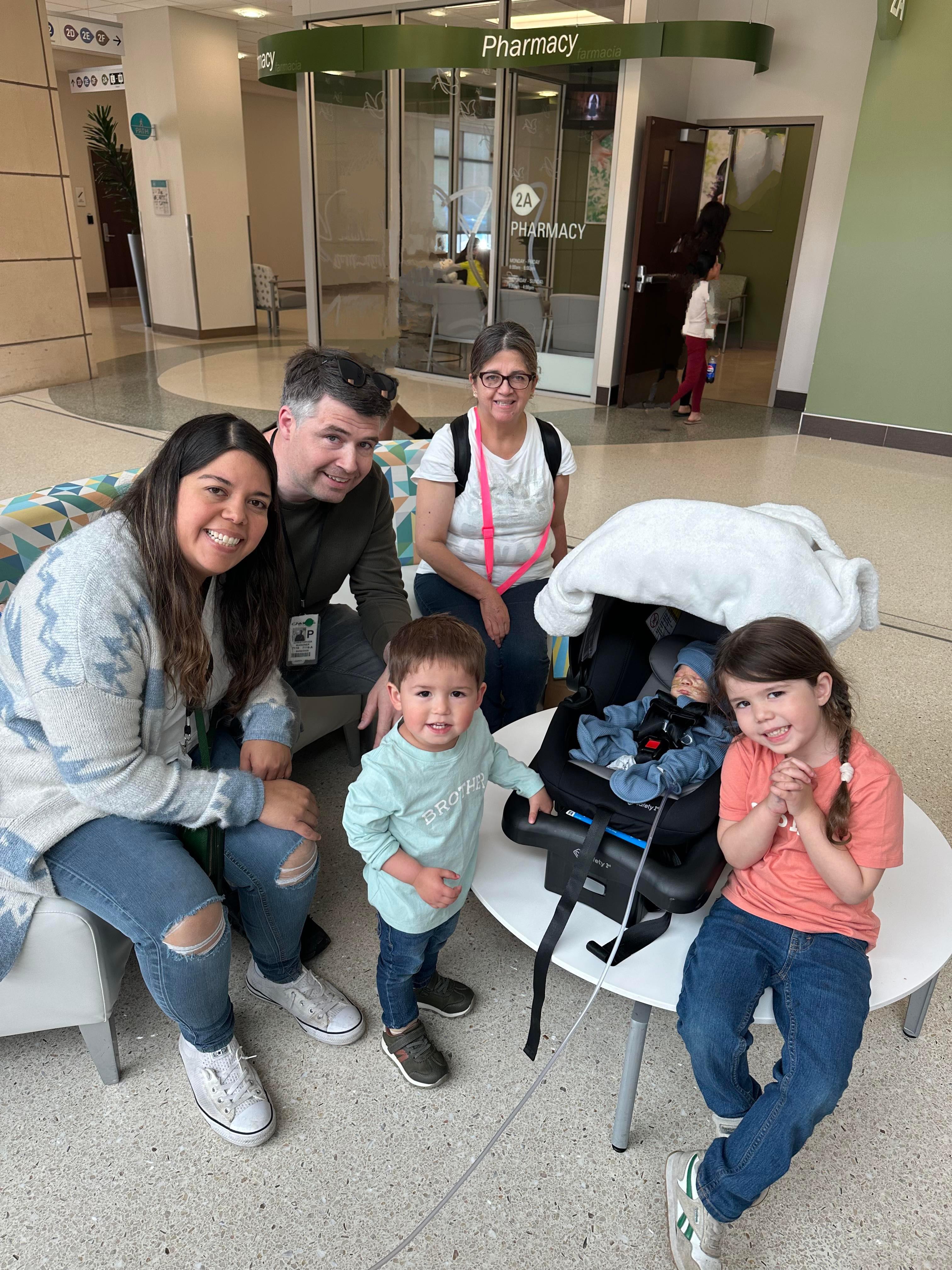 Children playfully interact with adults in a bright hospital waiting area during family visit.