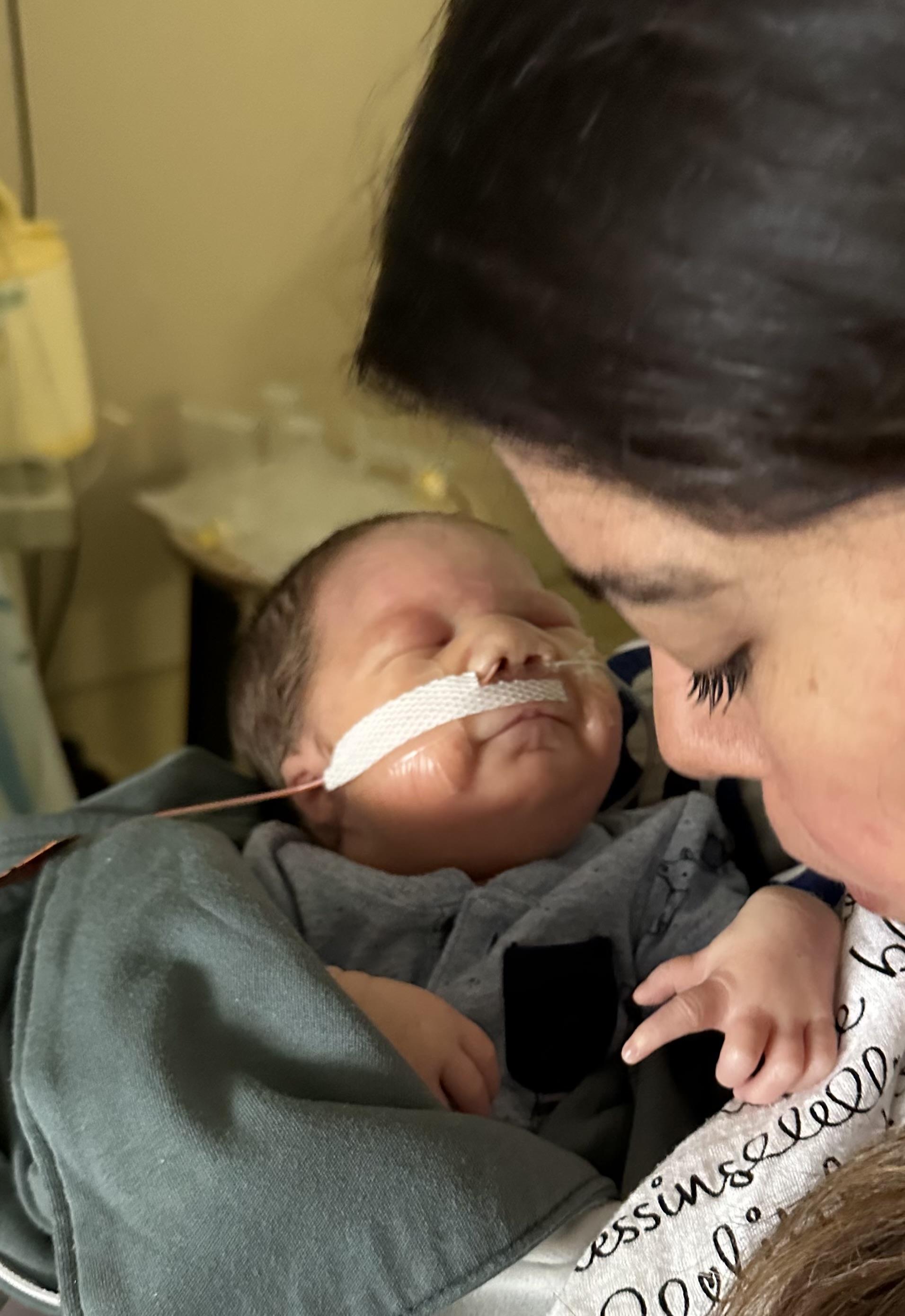 A mother comforts her newborn in a medical setting during treatment.