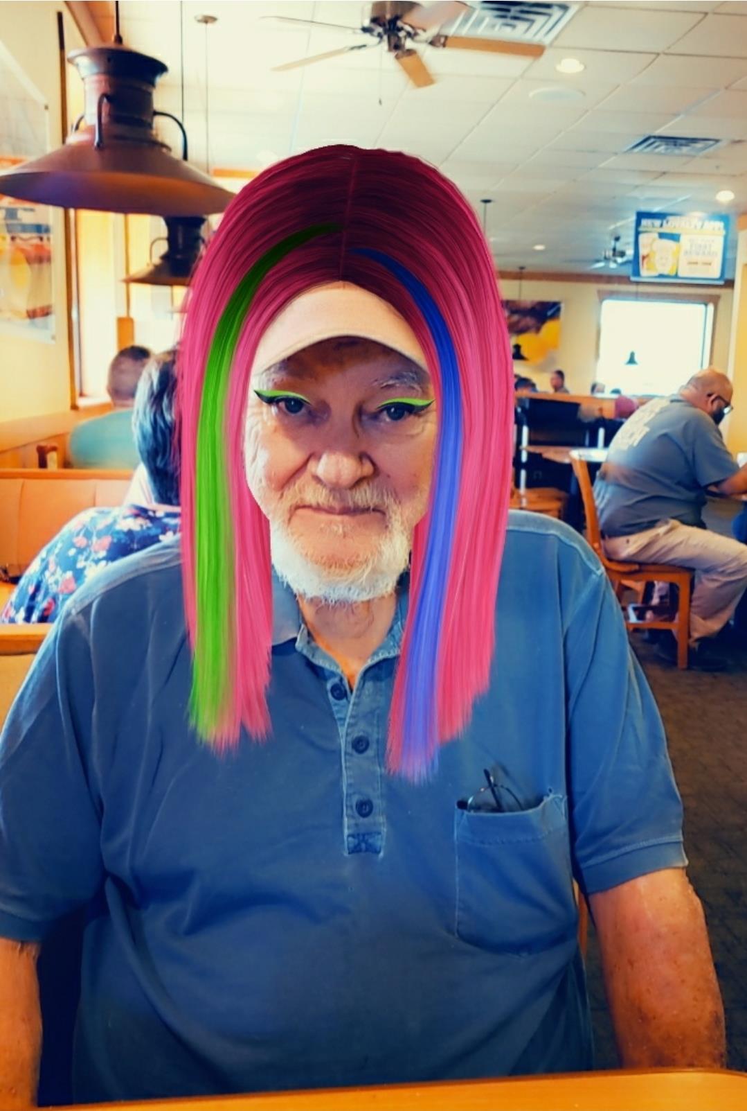 A man with a distinctive colorful wig, sitting at a table in a busy eatery during lunch hour.