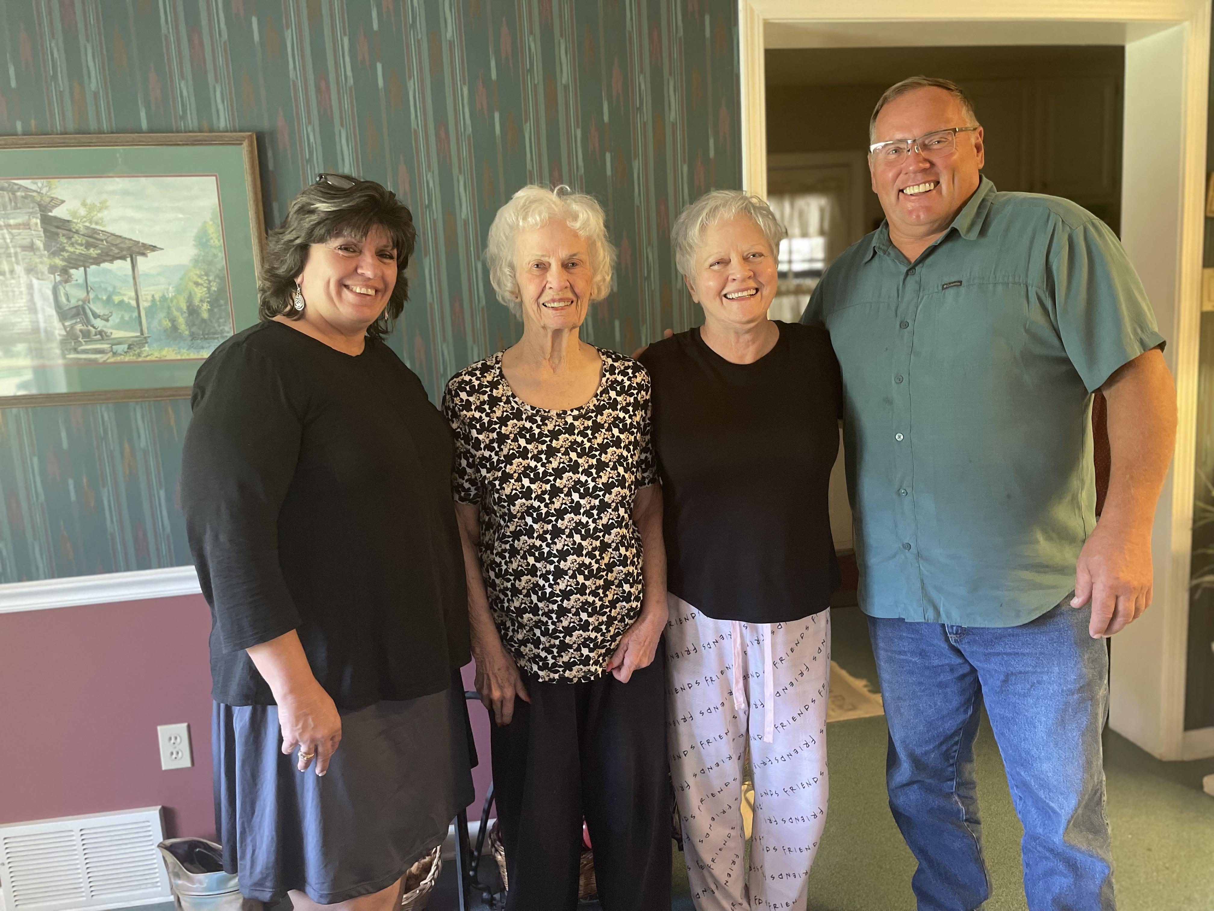 A family gathering in a cozy living room features four smiling relatives sharing joy.